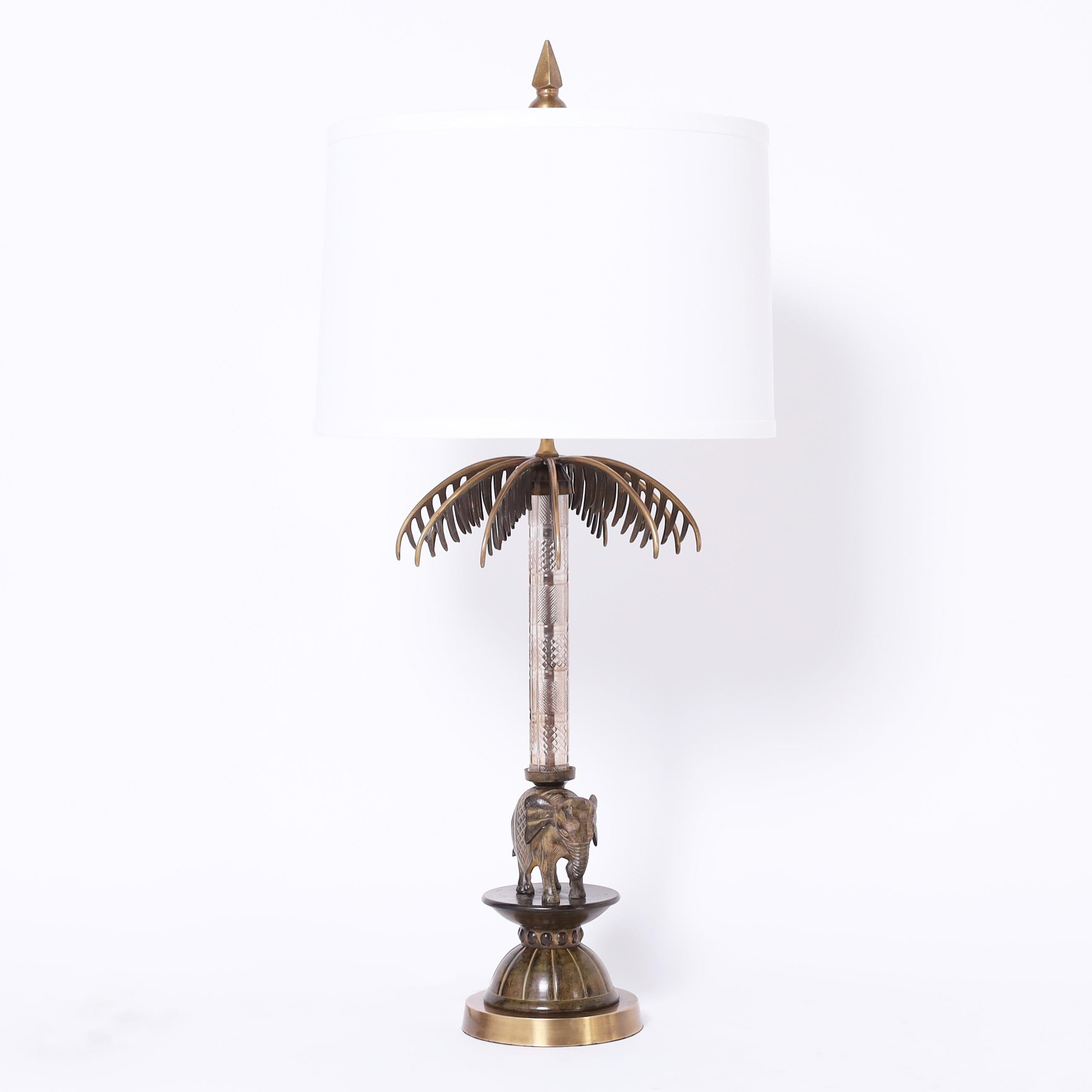 Impressive pair of British Colonial style table lamps with a combination of modern and tradition having stylized bronze finials and palm fronds on a glass post over cast bronze elephants on chic art deco inspired pedestals.