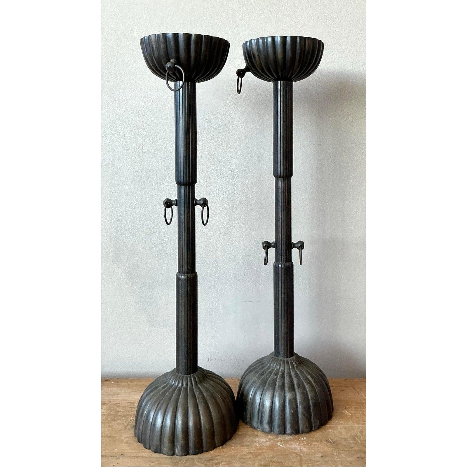 Questi alti candelieri vintage presentano steli scanalati a colonna e basi smerlate che richiamano le forme architettoniche classiche. Ogni pezzo è arricchito da anelli di ferro decorativi in due punti, che aggiungono un tocco leggermente