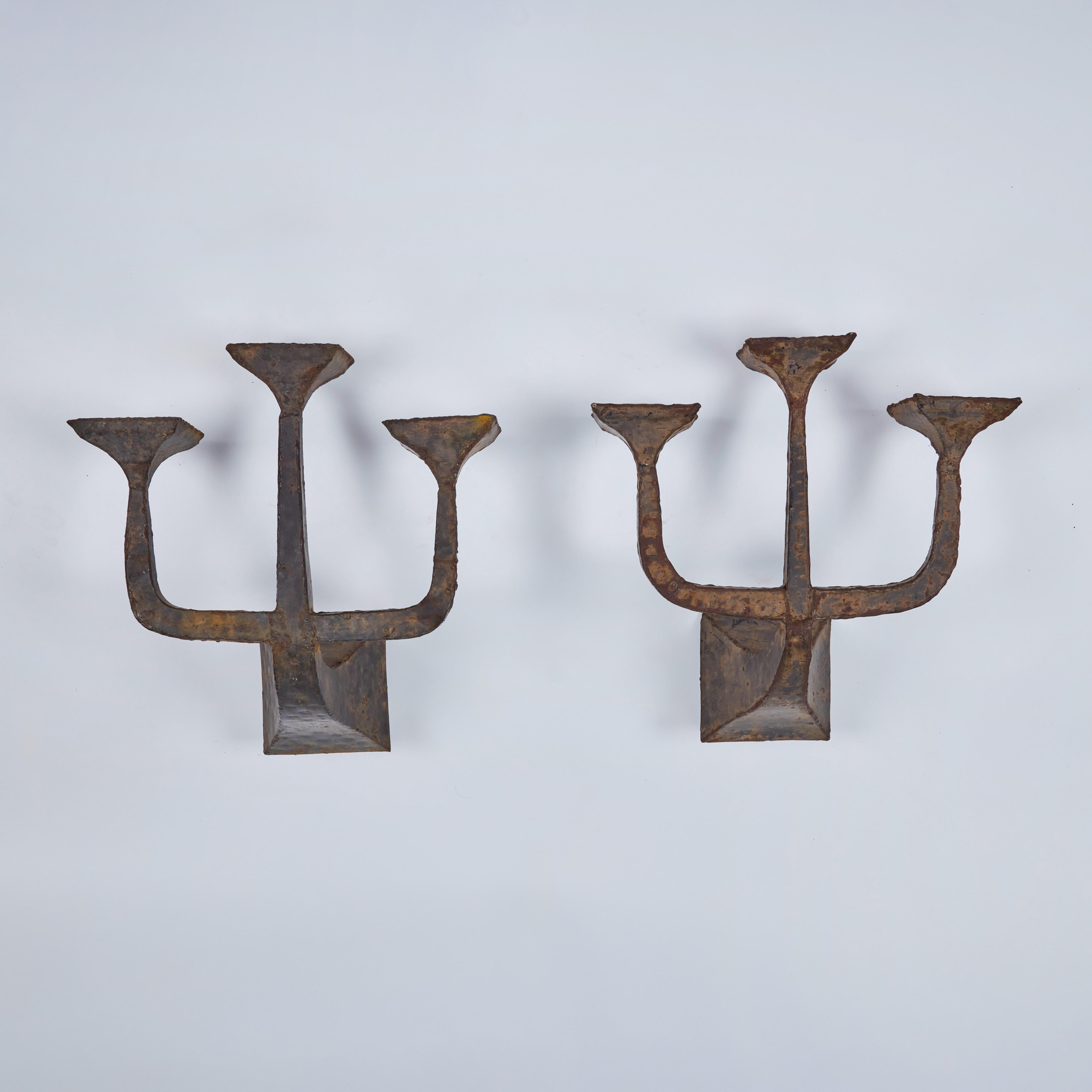 Striking pair of vintage brutalist three-lite sconces embodies the raw, architectural aesthetic of the brutalist movement.  Crafted from robust, weathered metal, the wall sconces feature a minimalist design with strong geometric forms,