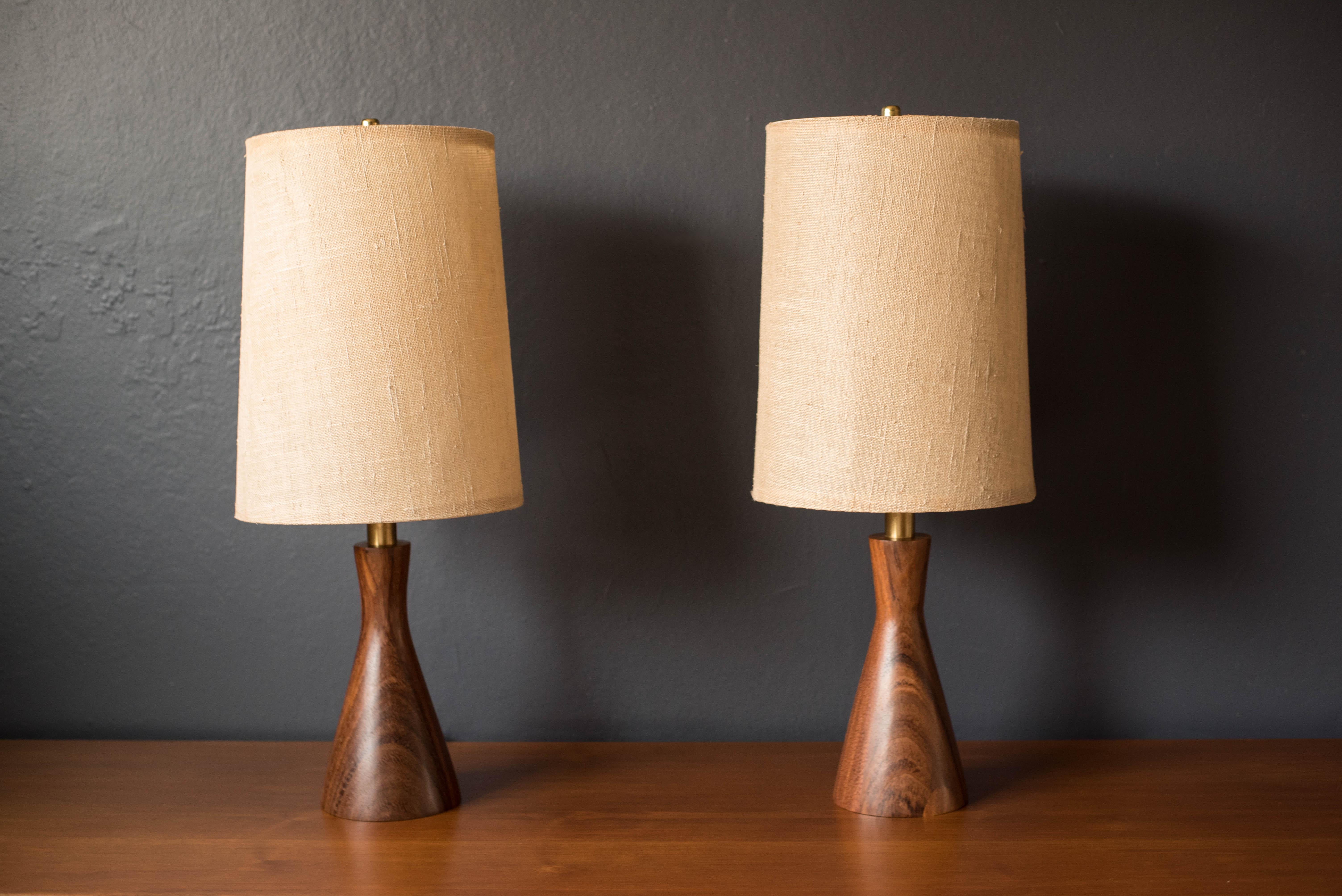Mid century pair of table lamps designed by Raymond Pfennig for Zina Lamp Co. This unique lighting set features a sculptural mahogany wood base accented with brass hardware. Shades are not included.