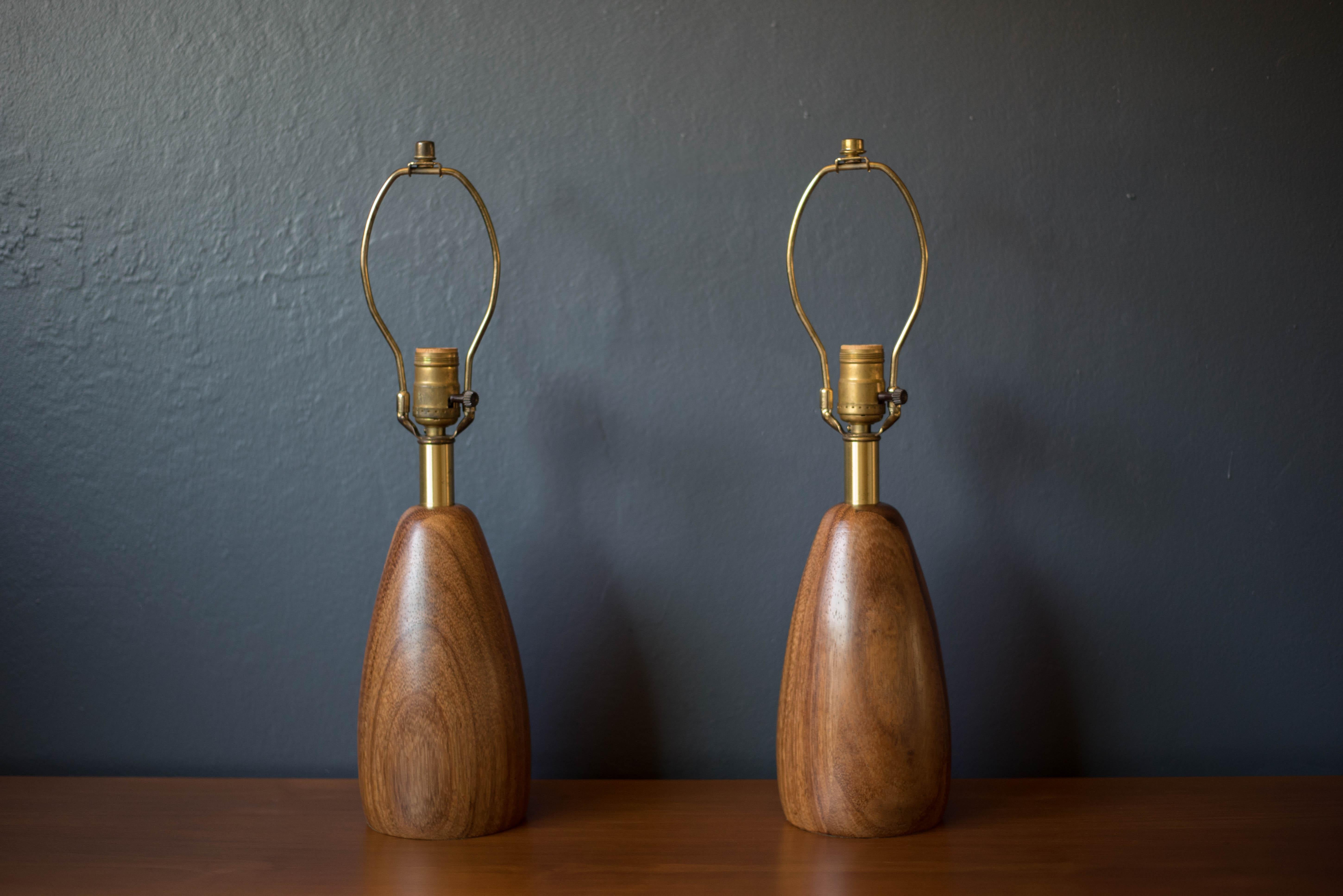Mid century pair of accent table lamps in mahogany designed by Raymond Pfennig for Zina Lamp Co. This sculptural set of two is accented with brass hardware and includes a three way switch.