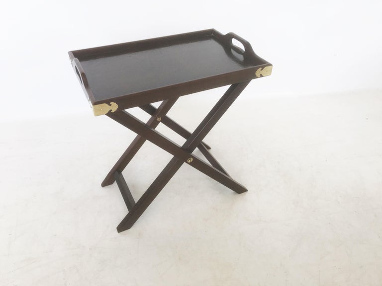This set of matching tables serving tray tables in Campaign styling. Made of walnut wood features a rectangular removable serving tray top with riveted handles, decorative brass details providing contrast against its wood finished frame. Rising on