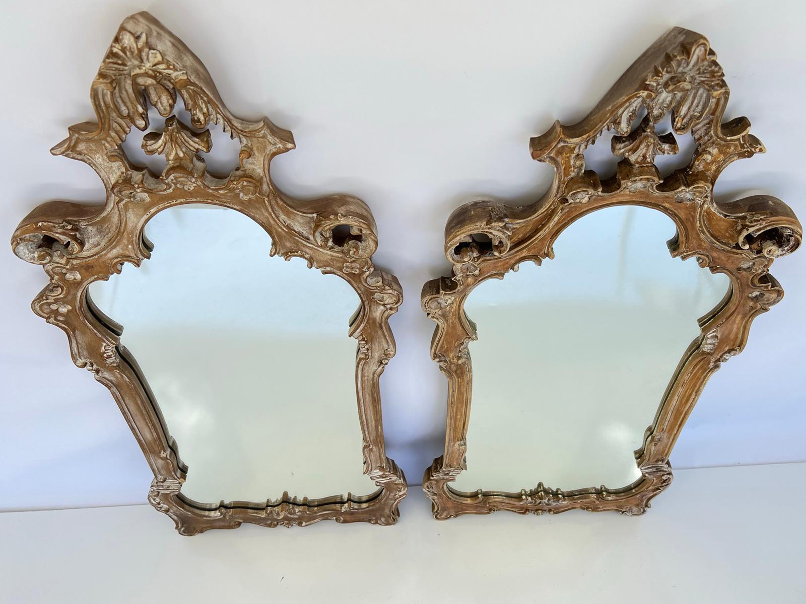 Pair of mirrors, having a pickled wood finish, each pierced frame carved in classical form, decorated with acanthus, combing, and rosettes. 

Stock ID: D1629.