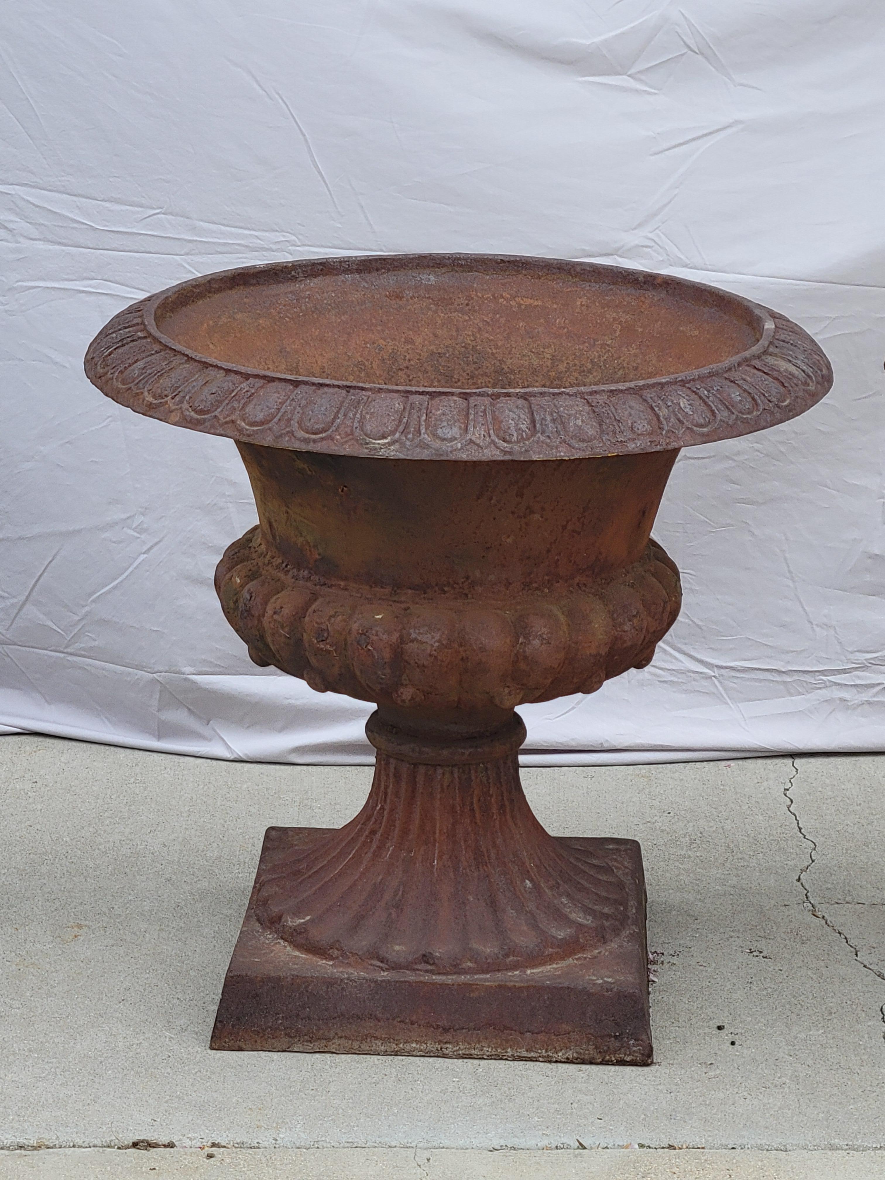 Una bellissima coppia di fioriere classiche monumentali in ghisa vintage con una patina arrugginita da decenni di permanenza all'esterno. Una coppia forte senza interruzioni. Ogni fioriera pesa circa 100 libbre. Non è difficile da spostare con un