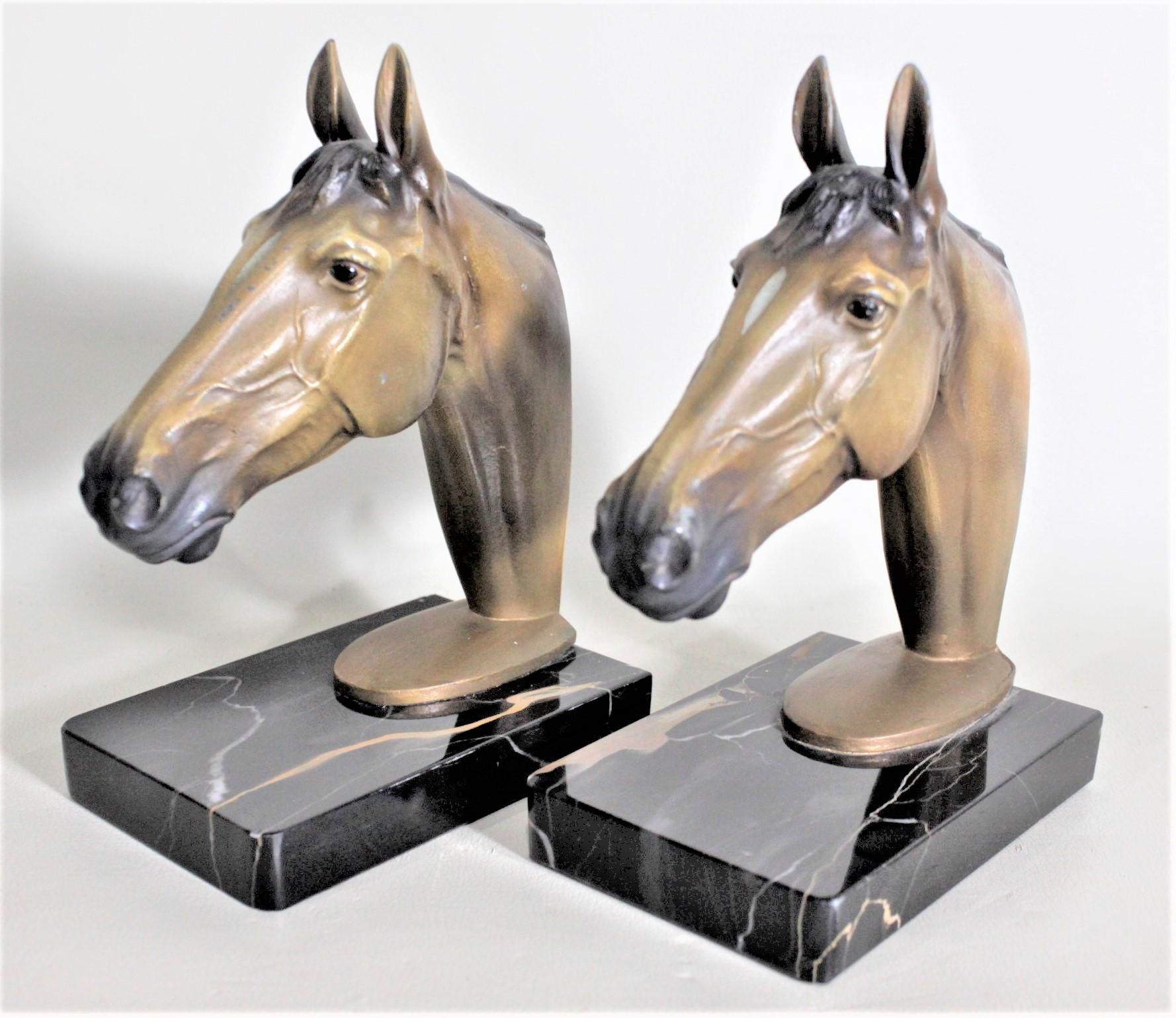 This pair of cast and cold-painted sculptural horse head bookends are unsigned, but presumed to have been made in England in approximately 1960 in a realistic style. The well executed cast and painted bookends are mounted on polished granite block
