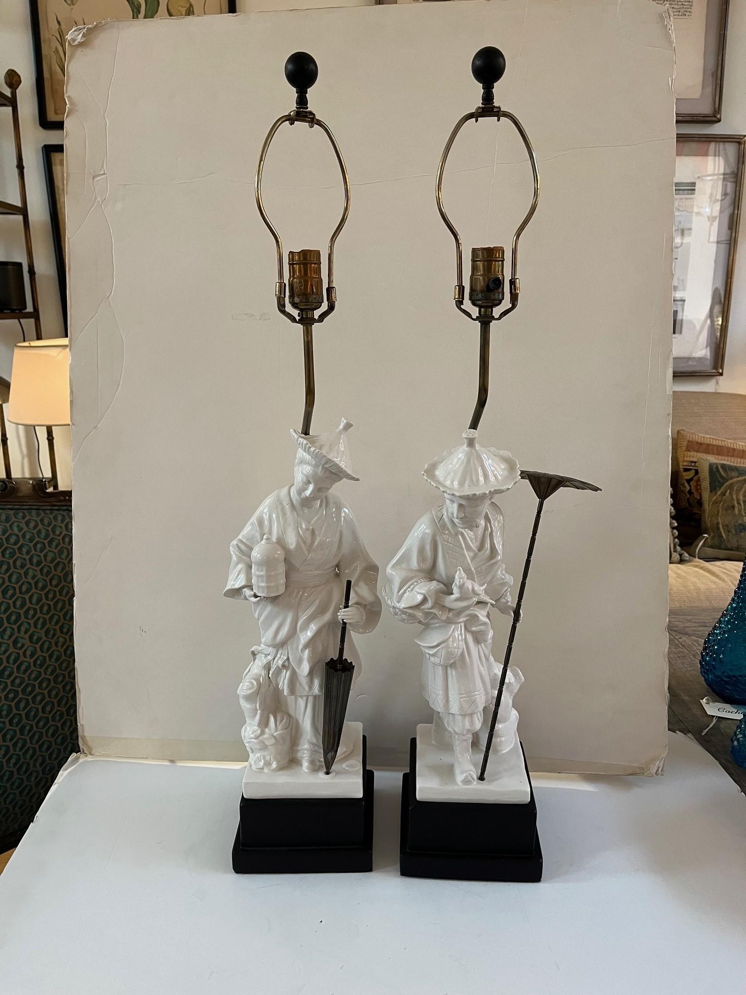 Pair of Vintage Chapman Porcelain Chinoiserie Figural Table Lamps, features Woman holding a Birdcage and a Parasole, and a Man with a Bird and Brass Parasole, the Lamps are in working Condition. Circa: 1973
