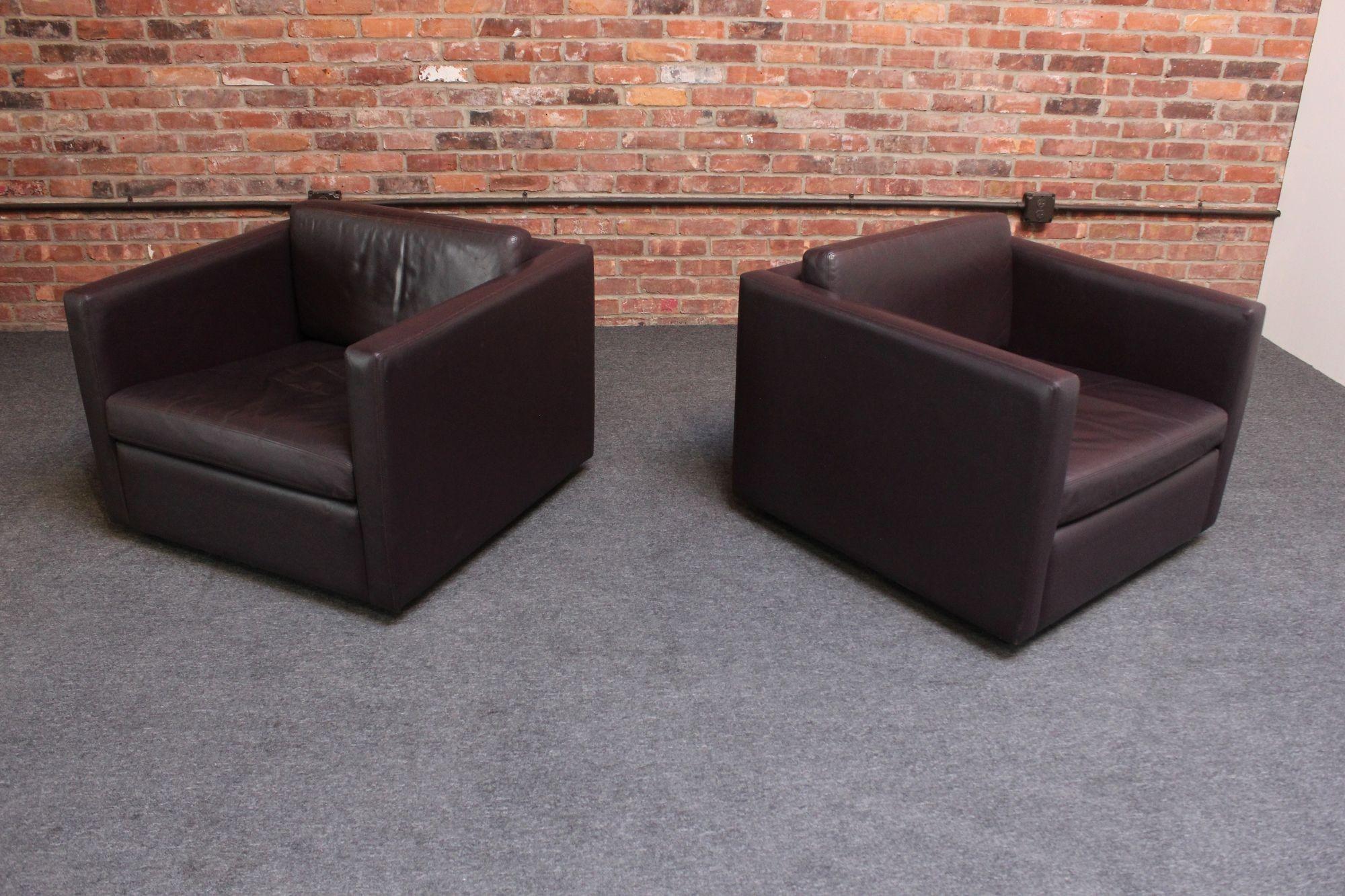 Pair of cube lounge / club chairs designed in 1971 by Charles Pfister for Knoll retaining their original 'eggplant' leather and ebonized steel block feet. Nicely proportioned design offering a sleek, modernist form and comfortable, luxe, beautifully