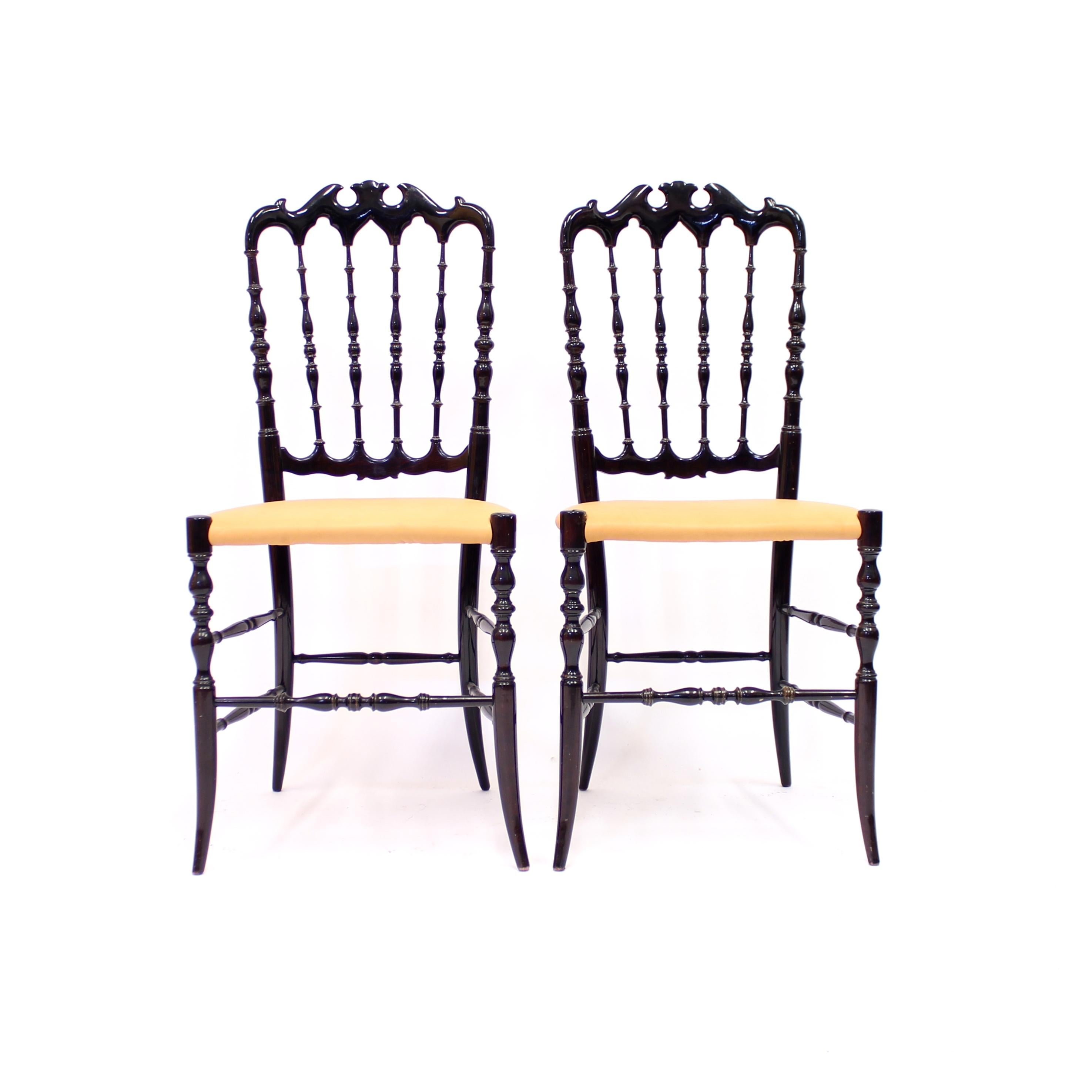 Pair of stained dark brown (almost black) vintage Chiavari chairs with newly upholstered leather seats, circa 1950. Most of the frame has lathed details. Newly upholstered in vintage leather so will have some nice light patina. Good vintage