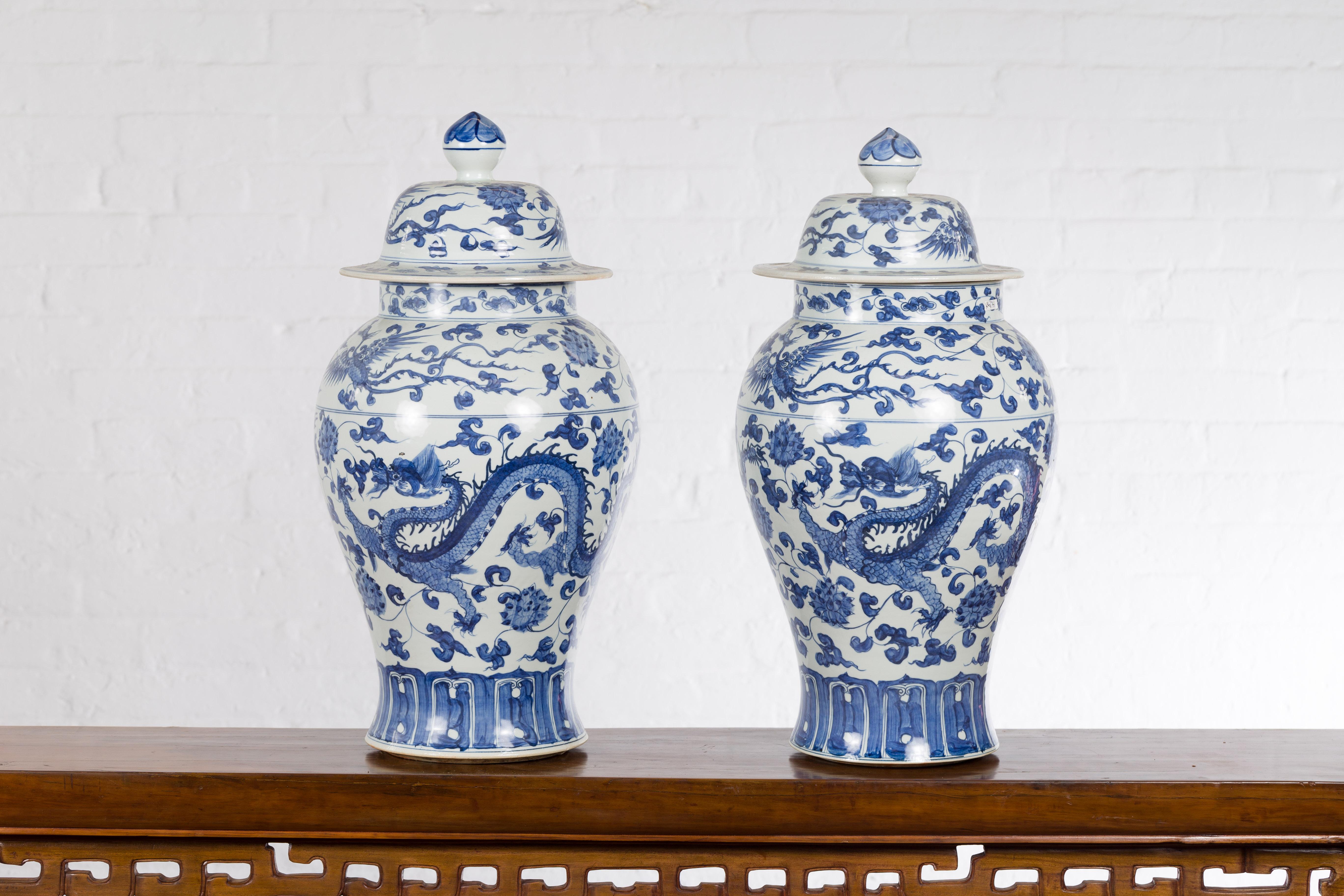 A pair of vintage Chinese blue and white porcelain lidded jars from the mid 20th century, with dragon motifs. Created in China during the midcentury period, each of this pair of blue and white porcelain jars features an elegant décor showcasing