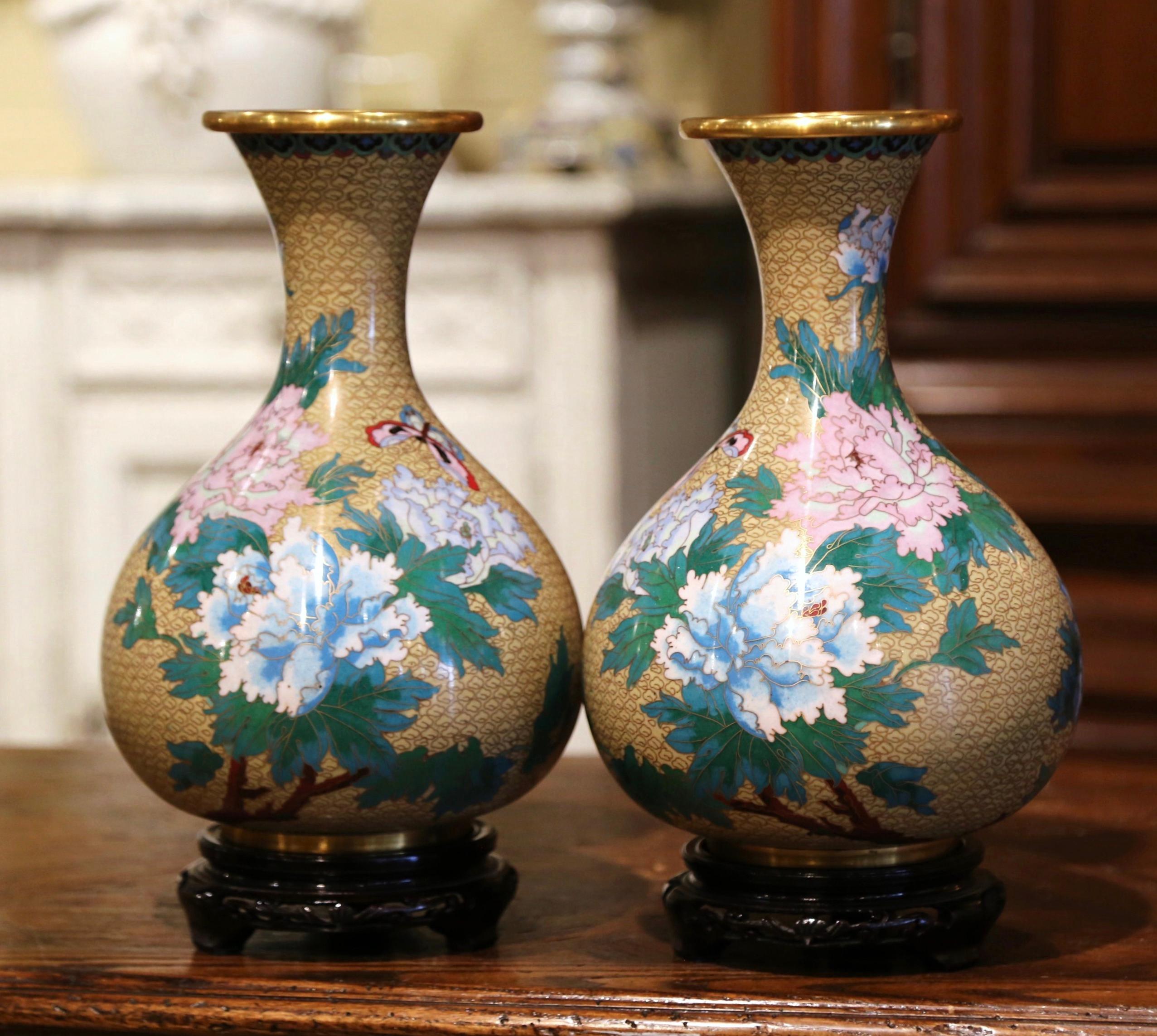 Decorate a mantel with this colorful pair of baluster vases; created in China circa 1980, each vase sits on a carved ebonized wood stand and features floral and butterfly motifs in the cloisonné technique (decorative work in which enamel, glass, or