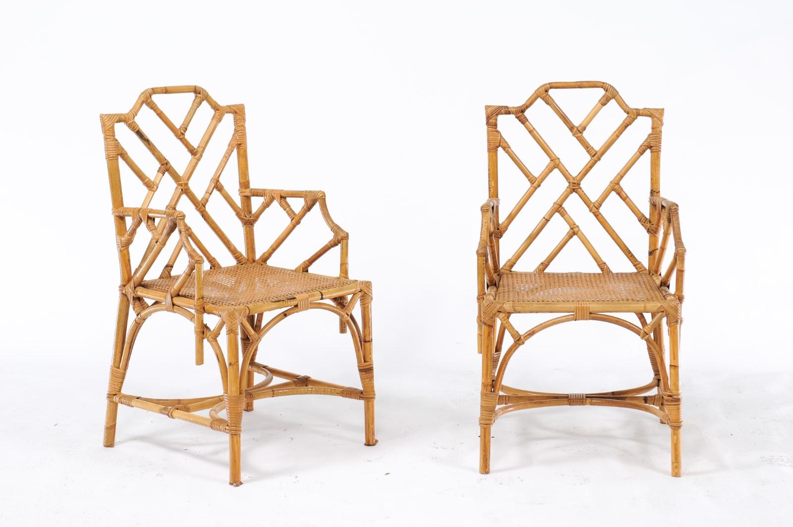 A pair of English vintage Chinese Chippendale style rattan armchairs from the mid-20th century with latticed arms and backs and curved cross stretchers. We are always on the lookout for pretty, midcentury rattan chairs, and this pair of Chinese