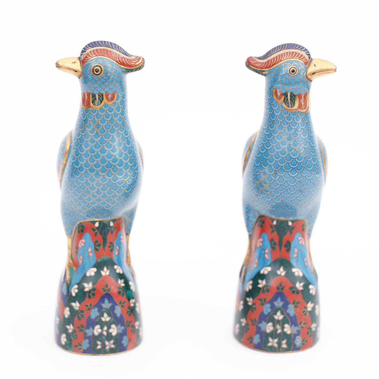Intriguing pair of vintage Chinese cloisonne or enamel on brass birds with quizzical expressions, colorful wings and tails, blue bodies and floral bases.