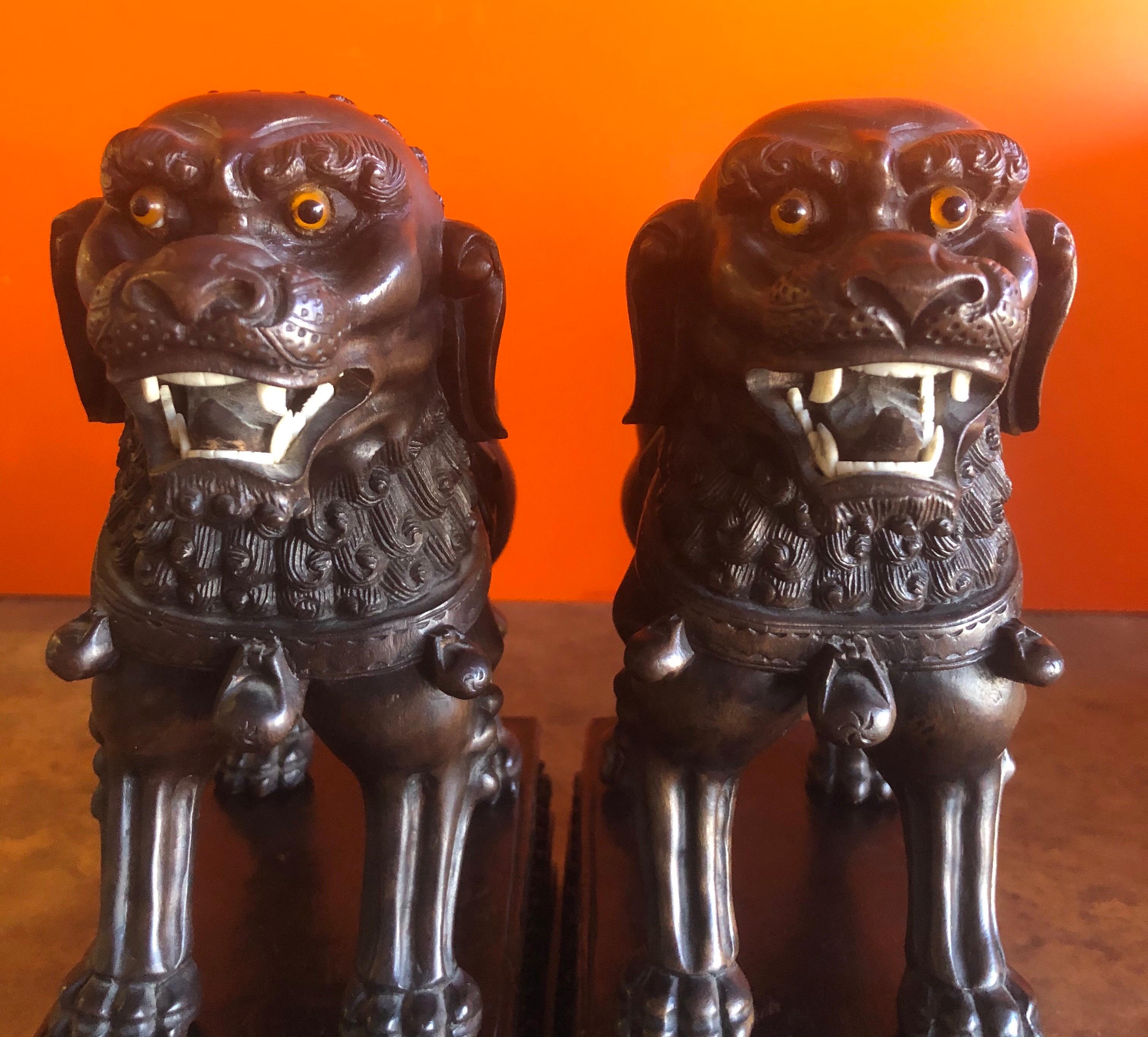 A very nice pair of vintage Chinese hand carved hard wood foo dogs or bookends which I believe are made from elm, rosewood or another type of hardwood, circa 1950s. The dogs have glass eyes and bone teeth (I believe) and are removable from their