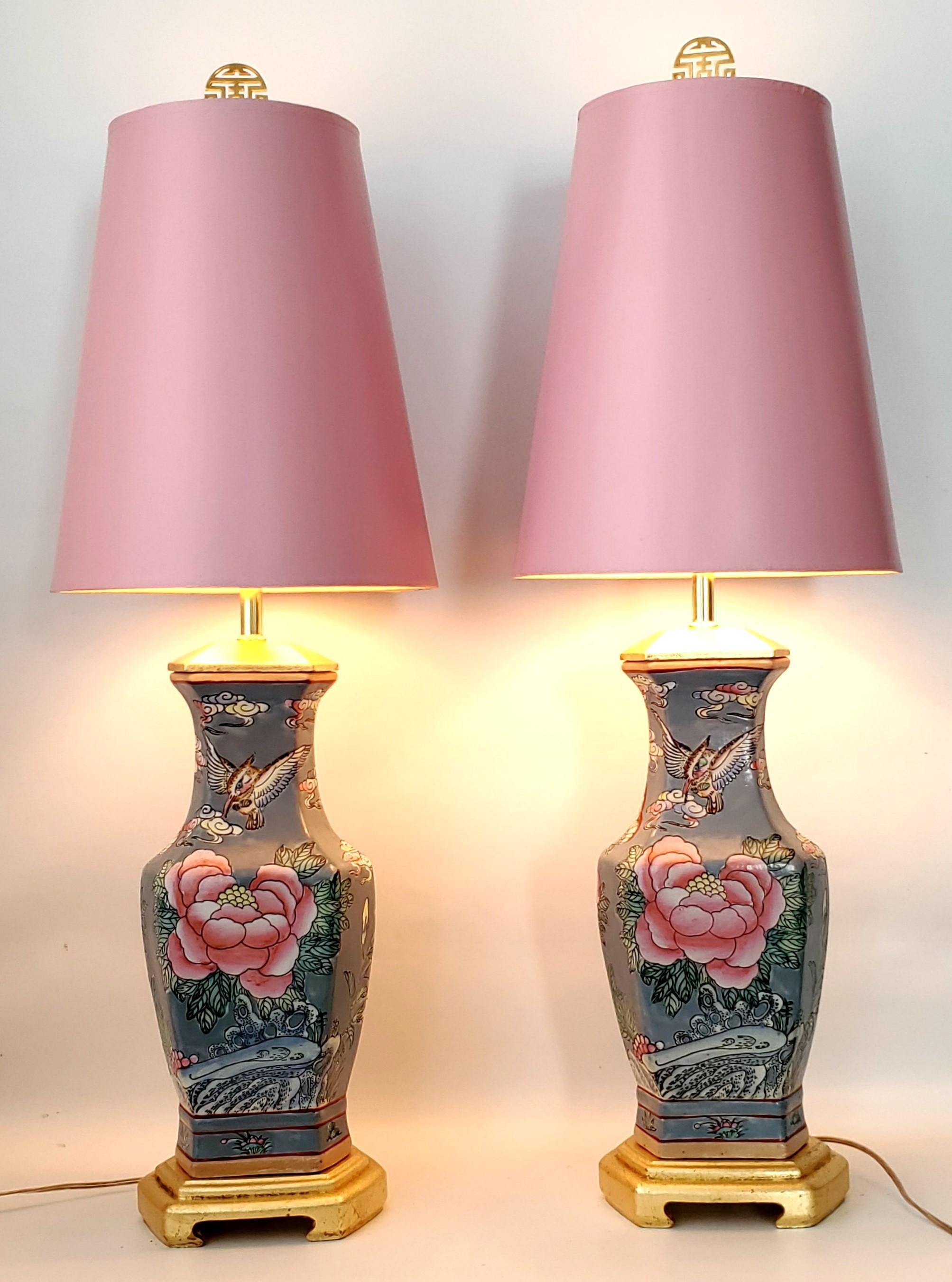 Pair of vintage Chinese porcelain table lamps with vintage pink shades. 
The bodies of the lamps are a gray/blue color with pink roses and butterflies on the front and lavender flowers and butterflies on the back. Old red-iron Chinese symbol on the