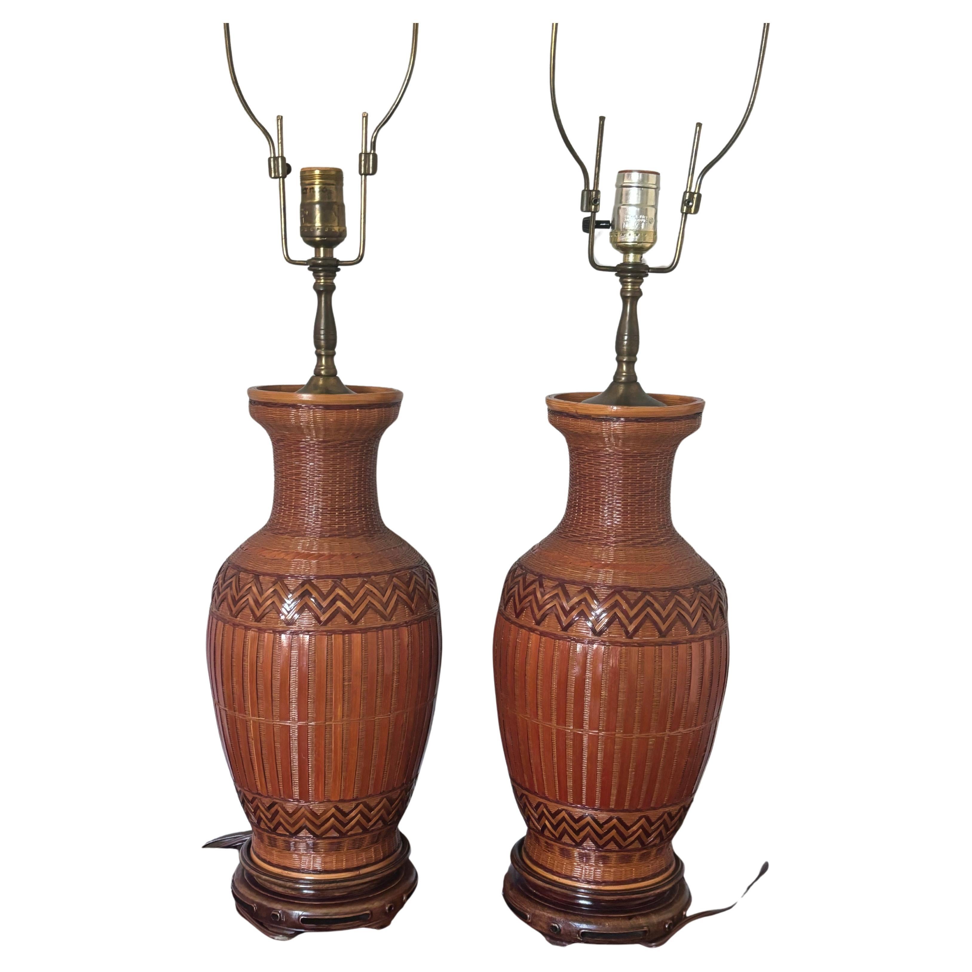 Stunning pair of early 20th century lamps. Crafted from vintage wicker wrapped porcelain vases. Beautifully hand crafted with a flowing classic organic shape. Solid carved wood bases and burnished brass fittings on top. Vintage adjustable height
