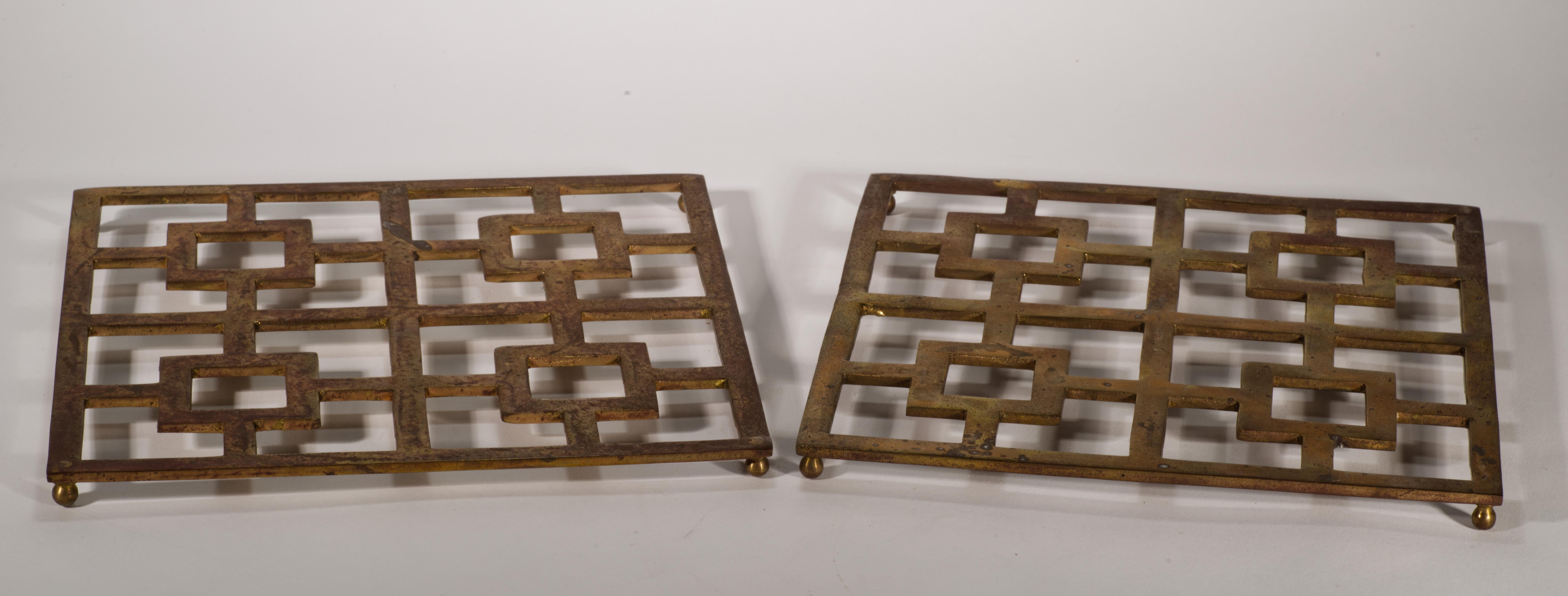 Ein Paar seltener Untersetzer mit Fuß aus Messing im asiatischen Stil mit grafischem, rechteckigem Chinoiserie-Muster; die Untersetzer sind auf kleinen Kugelfüßen montiert. 

Die Stücke sind auf der Rückseite mit dem Neiman Marcus-Logo und Made in