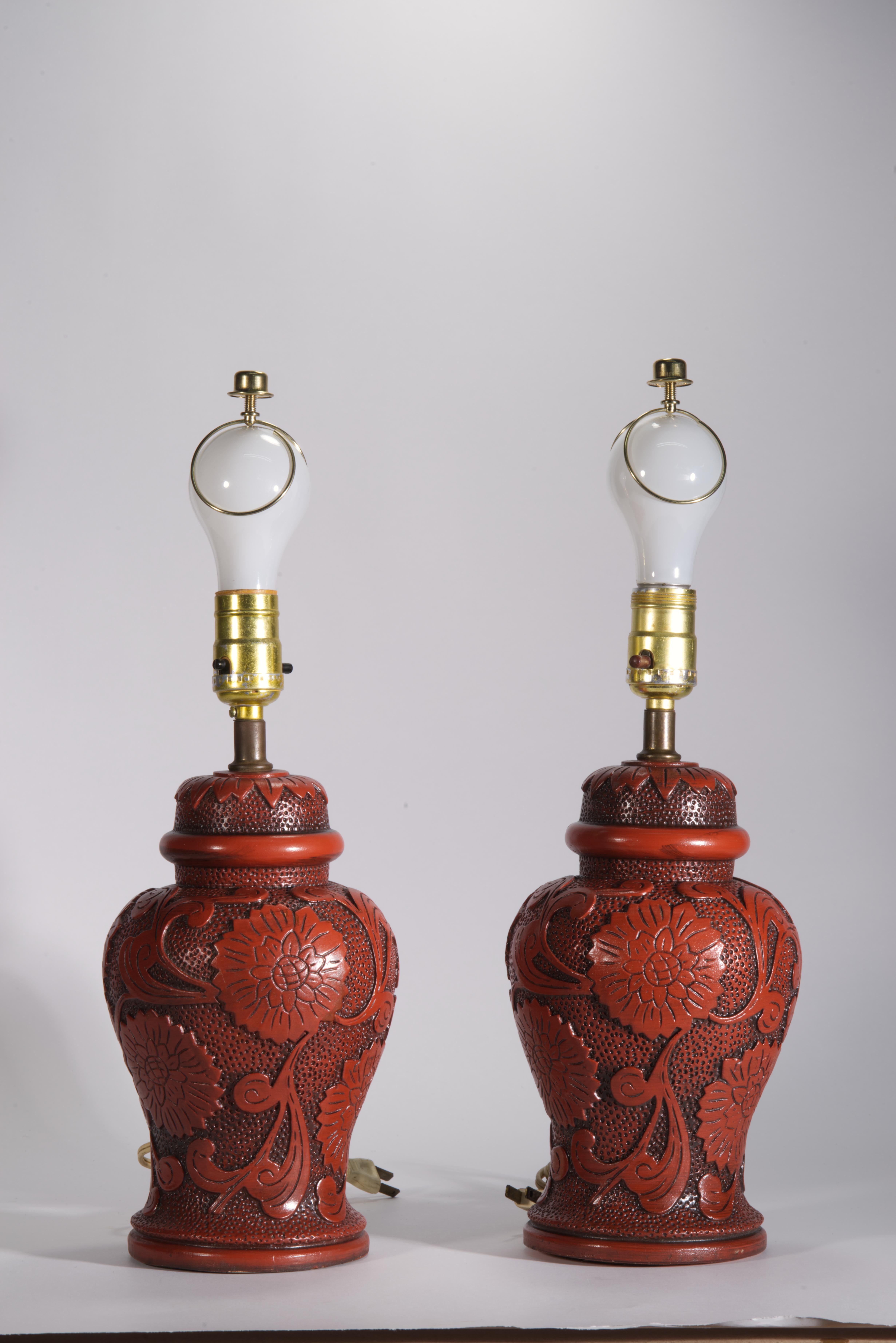 Paire de lampes de table ou d'appoint vintage en forme d'urne, avec des corps en faux cinabre ornés de guirlandes de fleurs avec des feuilles et des bandes de feuilles sur les couvercles de l'urne. La décoration graphique très détaillée dans le