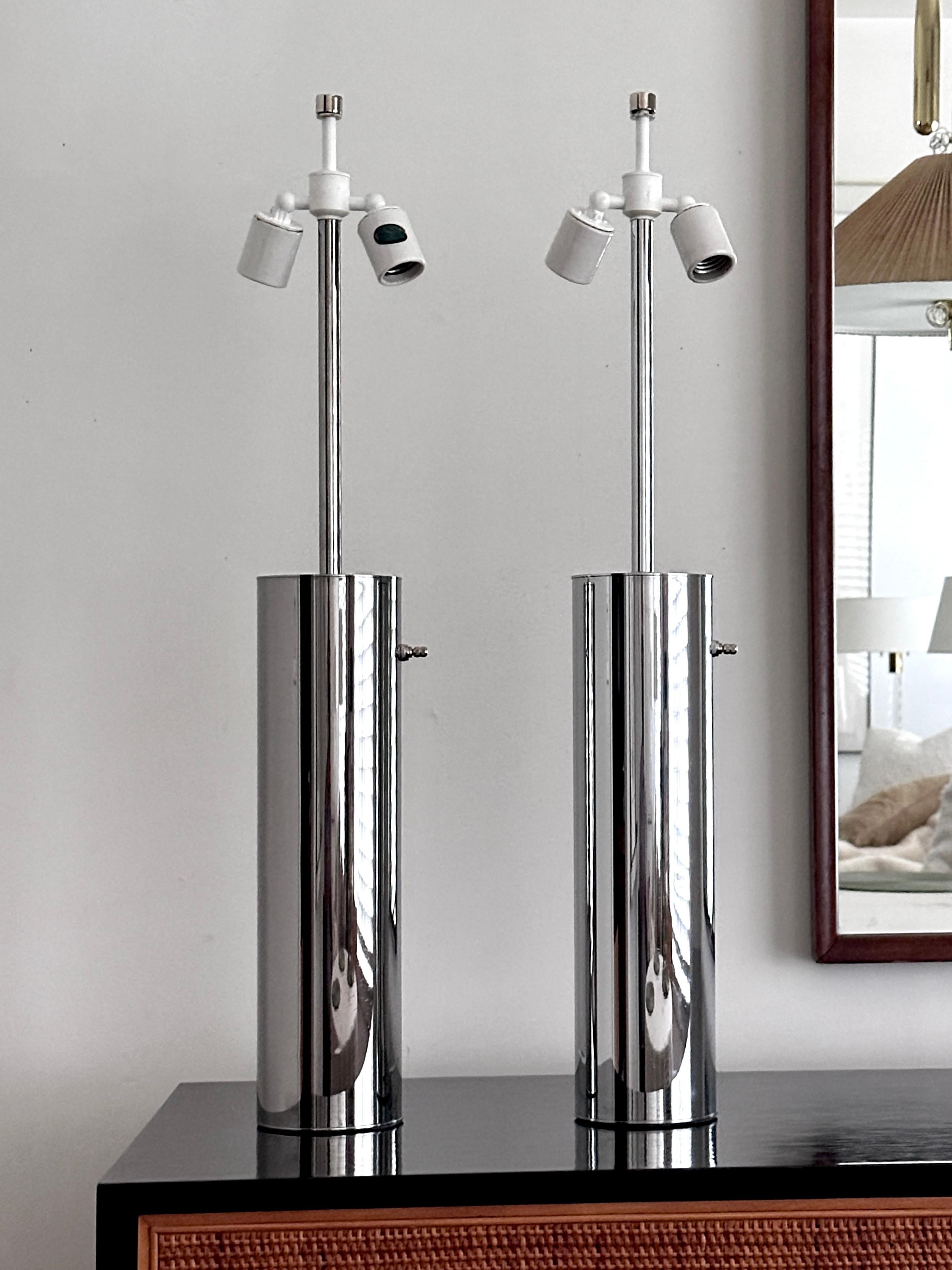 A pair of vintage chrome Nessen table lamps, chrome cylinders with heavy chrome disks on the top and bottom.  The pair have a three way switch which controls two sockets. The lamps are very well made and were suitable for both home and contract use.