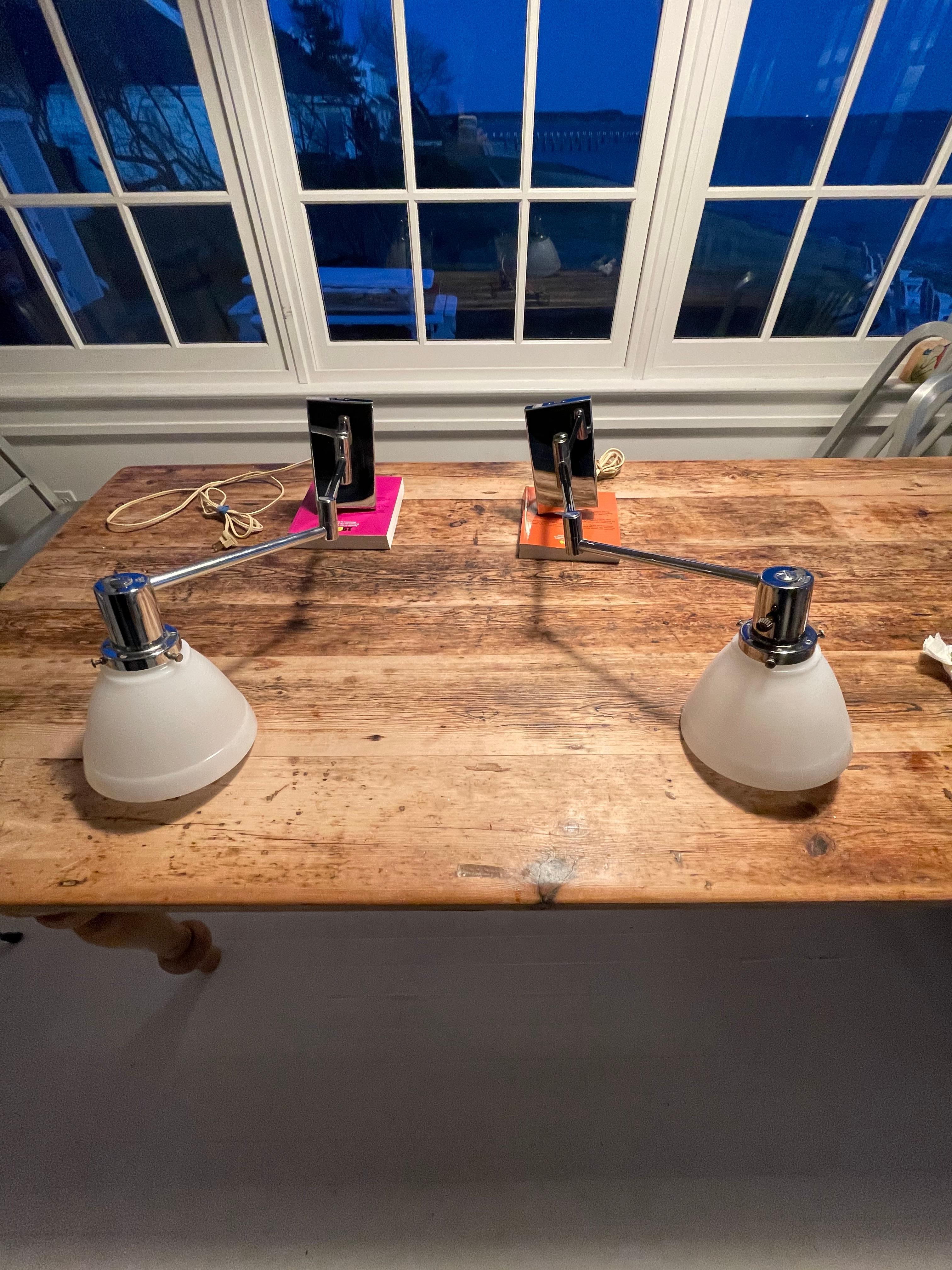 A rare pair of chrome Walter Von Nessen swing arm wall lamps .The arms articulate in different directions and lengths. The shades are milk glass. No mounting plates .Hardwired. Good condition .