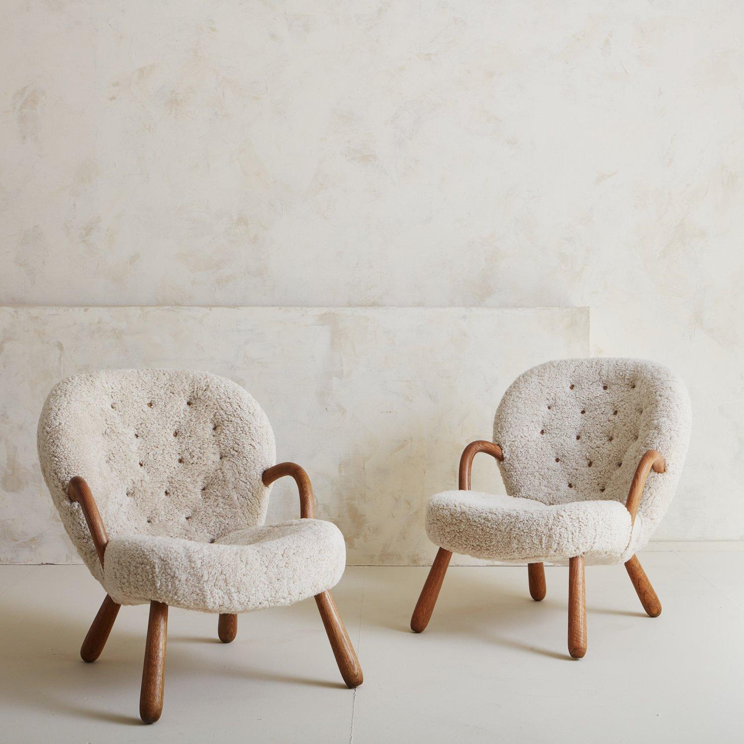 A pair of vintage Clam chairs designed by Danish architect Philip Arctander in 1944. These chairs were newly reupholstered in a luxe shearling with subtle tufting. We love the rounded arms, beech legs and curved shape on these incredibly comfortable