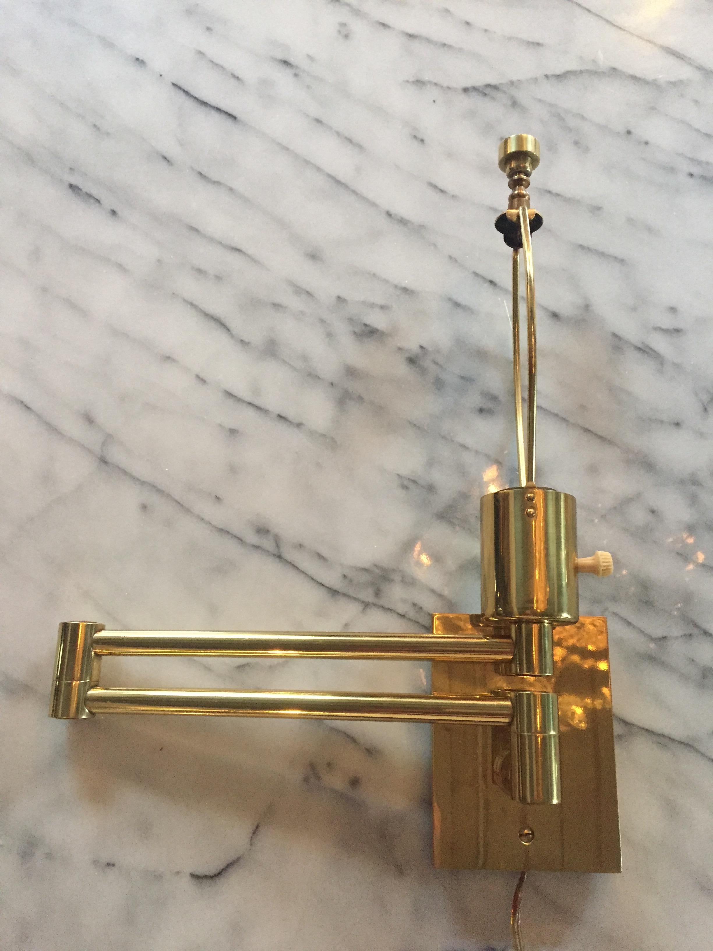 A classic vintage pair of polished brass double swing arm sconces with original harps and solid brass finials as well as solid brass column cord covers. Signed Hansen on original cast brass rectangular backplates (3 1/2