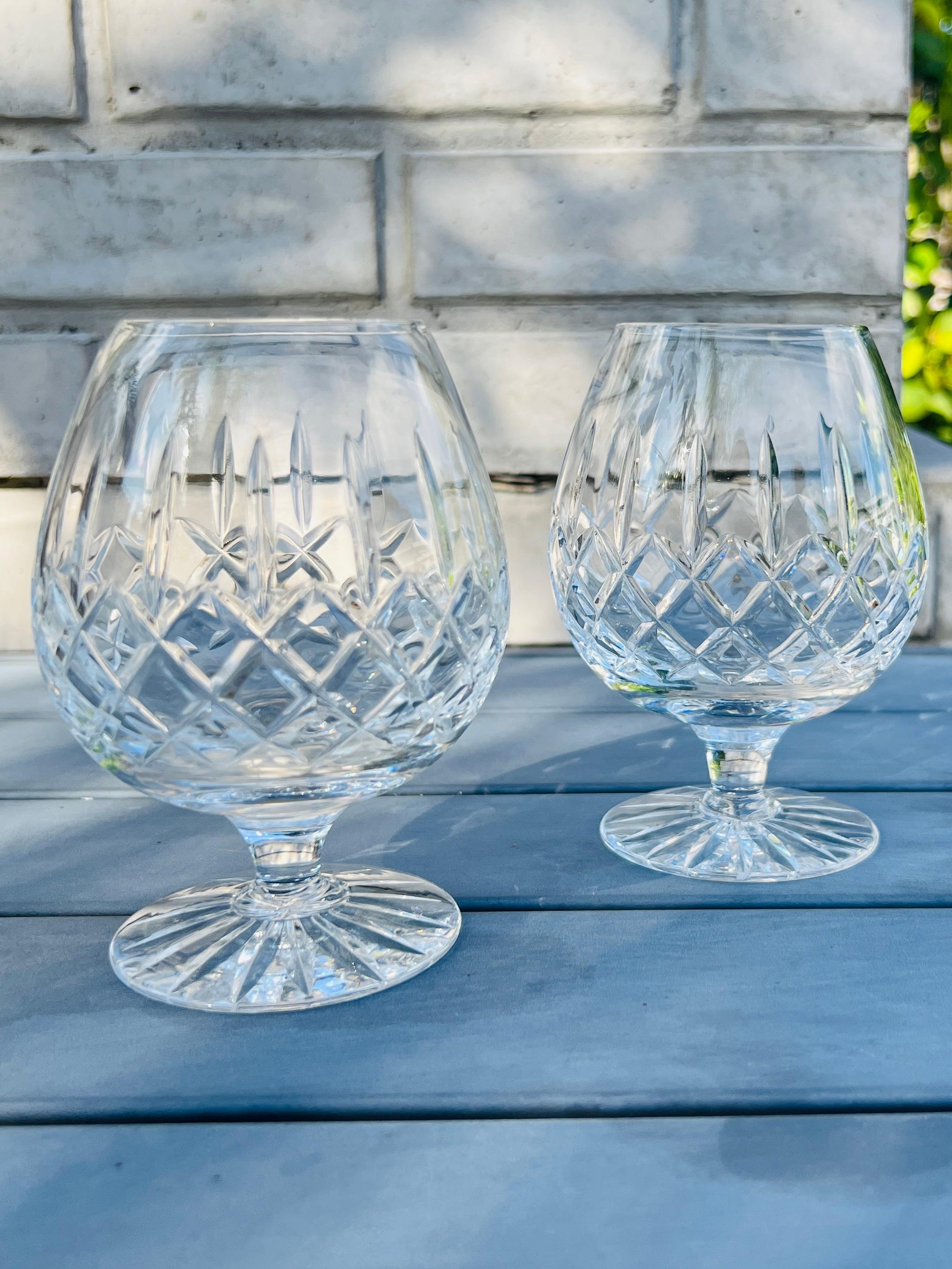 Pair of cut crystal brandy glasses by Waterford Crystal from the Lismore Series.  These glasses feature elegant balloon bowls with short stems ideal for swirling your favorite brandy or cognac.  Features the signature diamond and wedge cuts that the