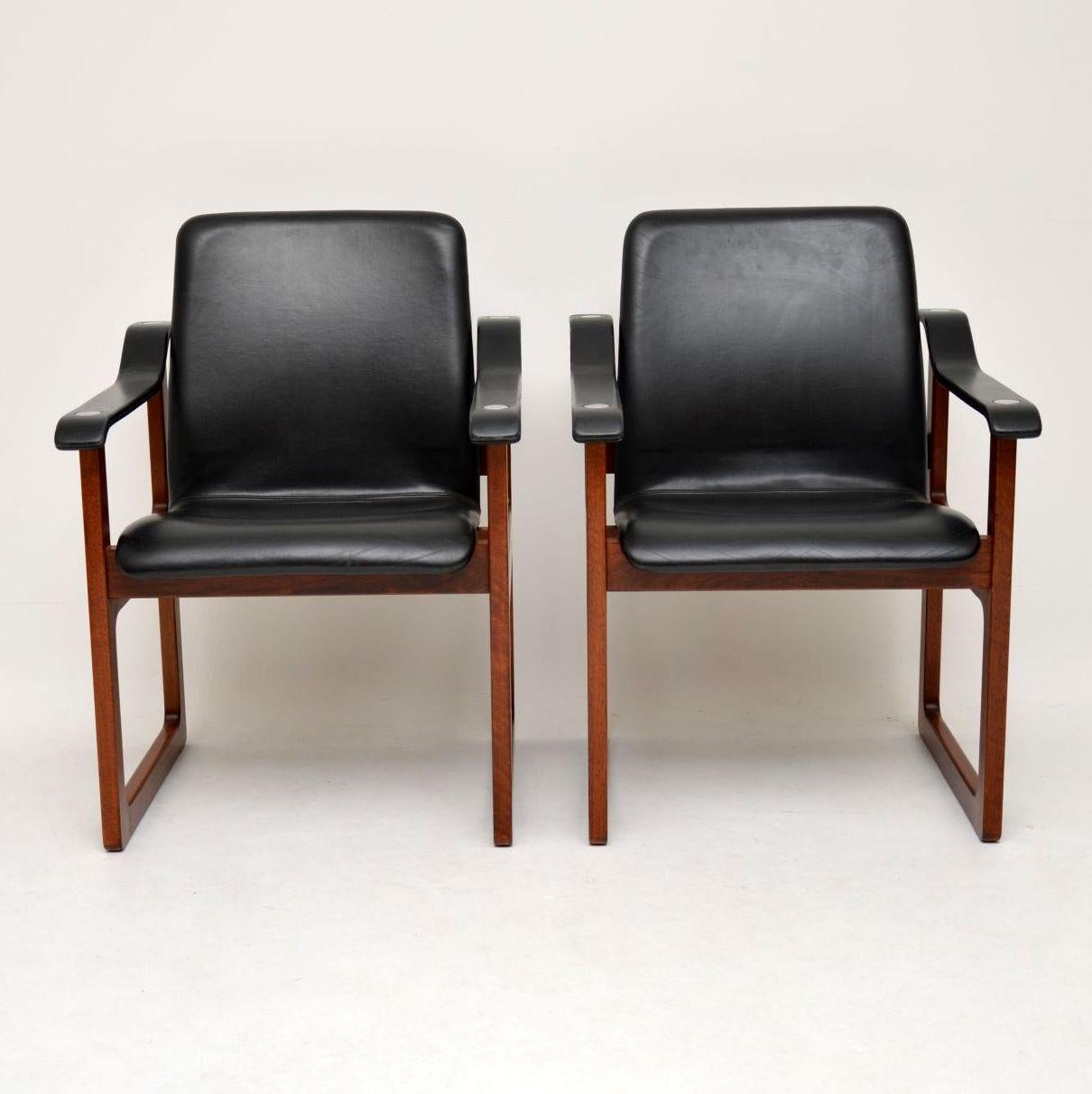 An absolutely stunning and very rare pair of vintage Danish armchairs in solid wood with black leather upholstery and chrome embellishments on the upper arms. These were made by Dyrlund, circa 1970s, we have never come across this model before.