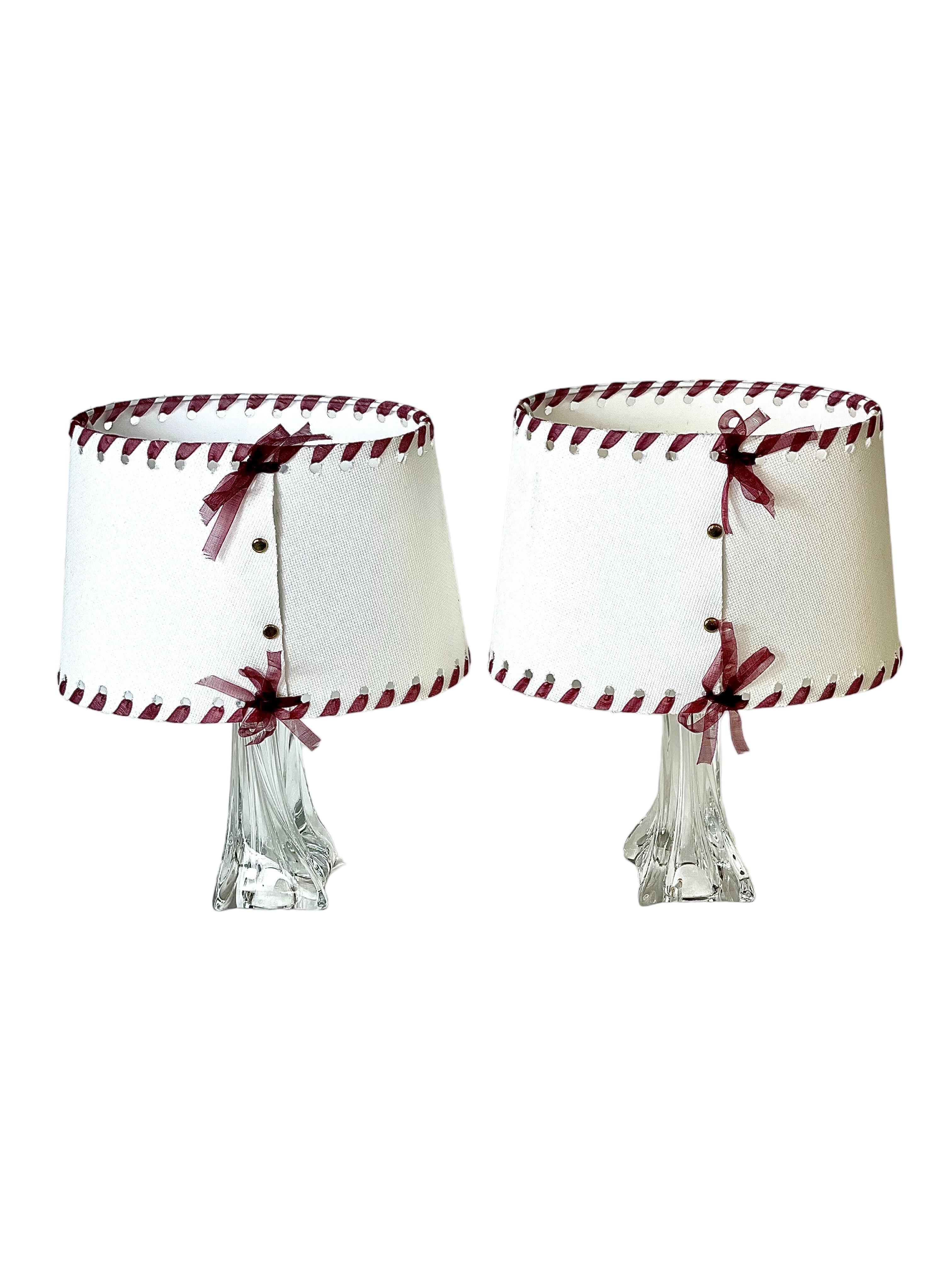 A pair of vintage French Daum crystal table lamps, from the legendary French Daum cristallerie. Their glorious, curved organic shape catches the light beautifully and forms a very stylish and heavy base. The cream canvas shades have a wine-red