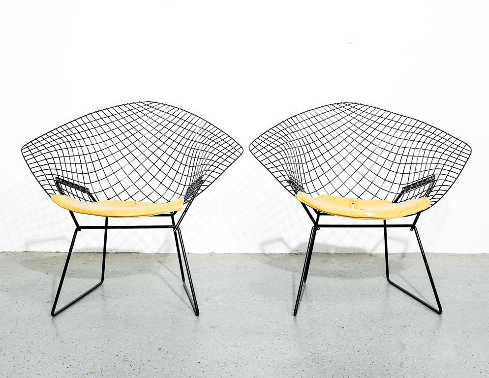 Vintage Diamond chairs designed by Harry Bertoia in the 1950s for Knoll. Black wire shells with matching black rod bases. Includes original mustard tone vinyl seat pads. Signed Knoll on seat pads. Sold as a pair. 16.5