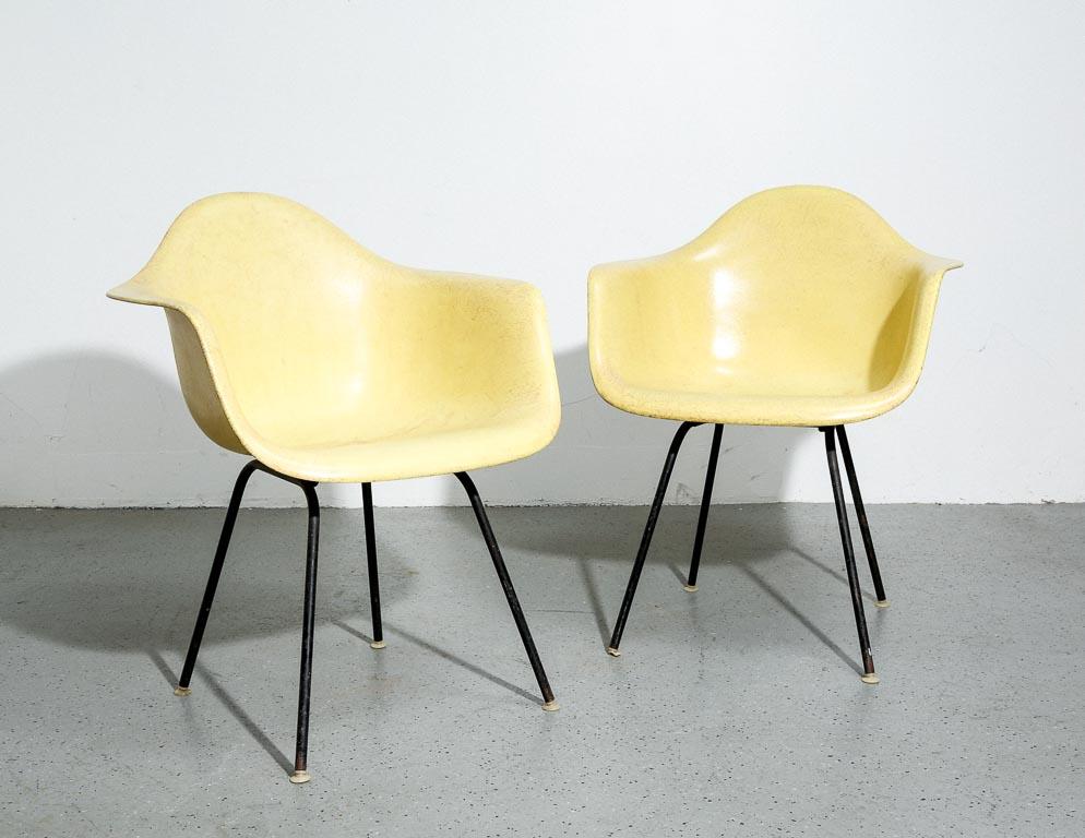 Coques de bras vintage Eames en fibre de verre ocre clair/jaune. Conçu par Charles et Ray Eames pour Herman Miller. Sur des bases H noires originales. Taches et décoloration sur les deux chaises et un éclat sur un bras.