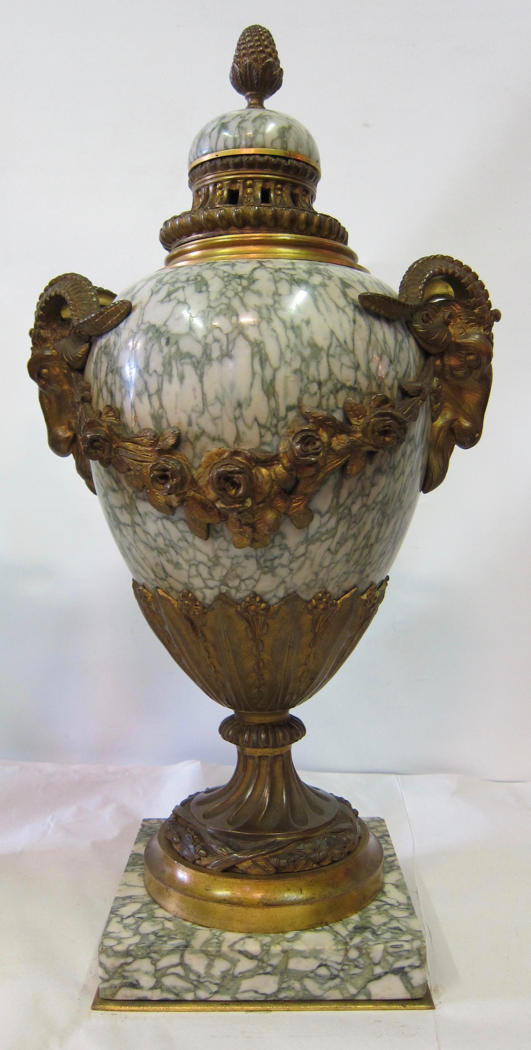 Finely crafted, highly polished Empire style veined green marble sectional baluster form urns. These elegant treasures feature patinated ormolu ram's head handles and are draped with rose garland ormolu swags. Each urn is mounted on a square marble
