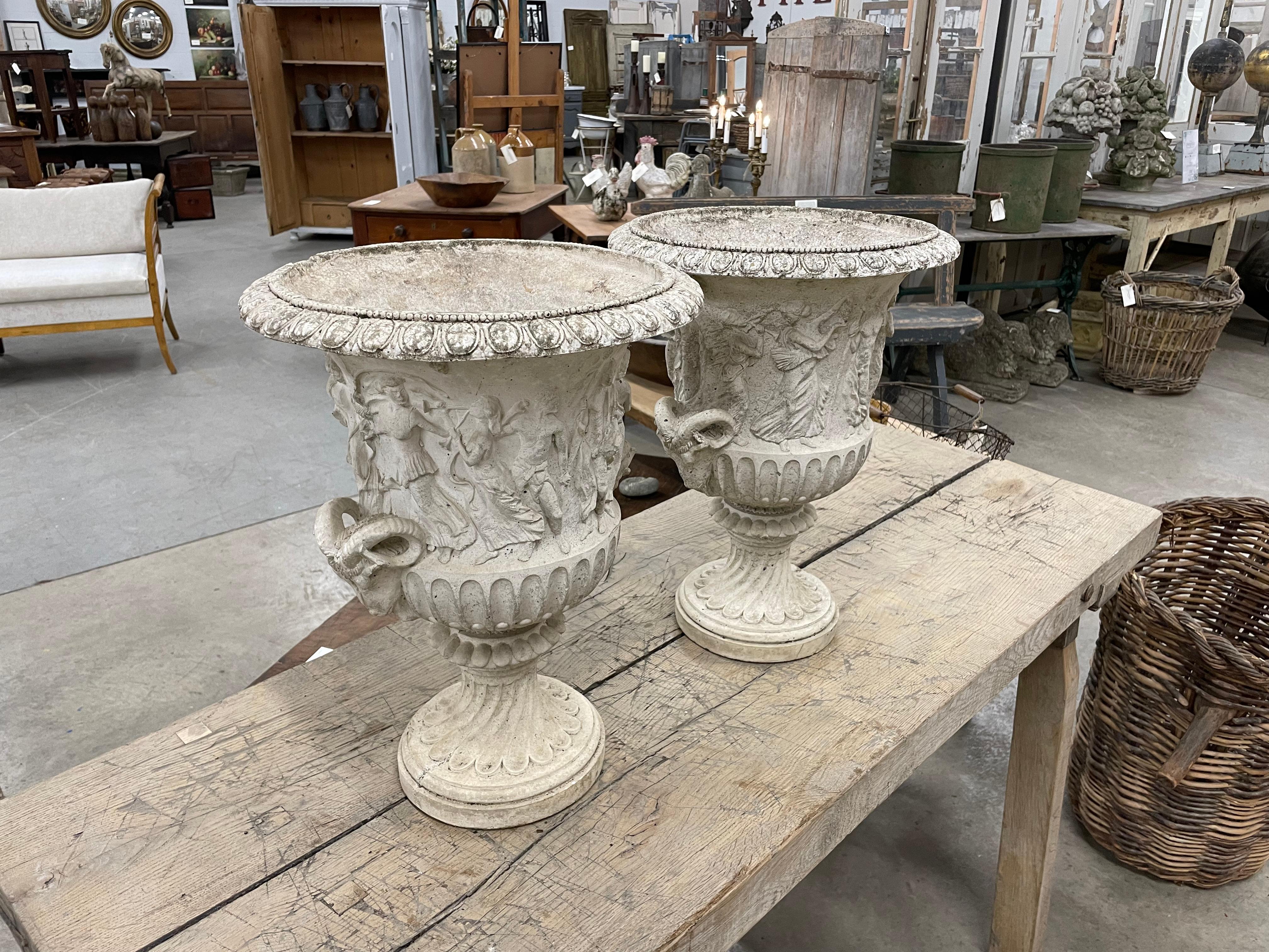 Pair of vintage Renaissance style Medici composite stone campana urns with relief decoration and figural scene, with ram's head handles on a spiral pedestal base.

The history of the original Medici urns dates back to antiquity, as they were