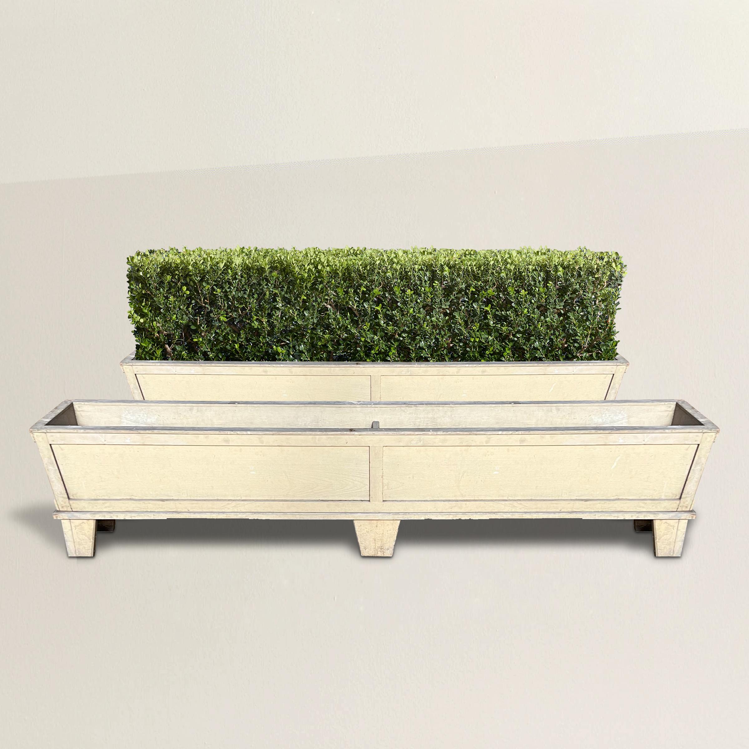 A pair of simple yet chic pair of 20th century English wood planters with tapered paneled sides with chamfered edges, and finished in a pale yellow paint. Perfect for flanking your patio or porch, or used indoors to grow herbs near your kitchen.