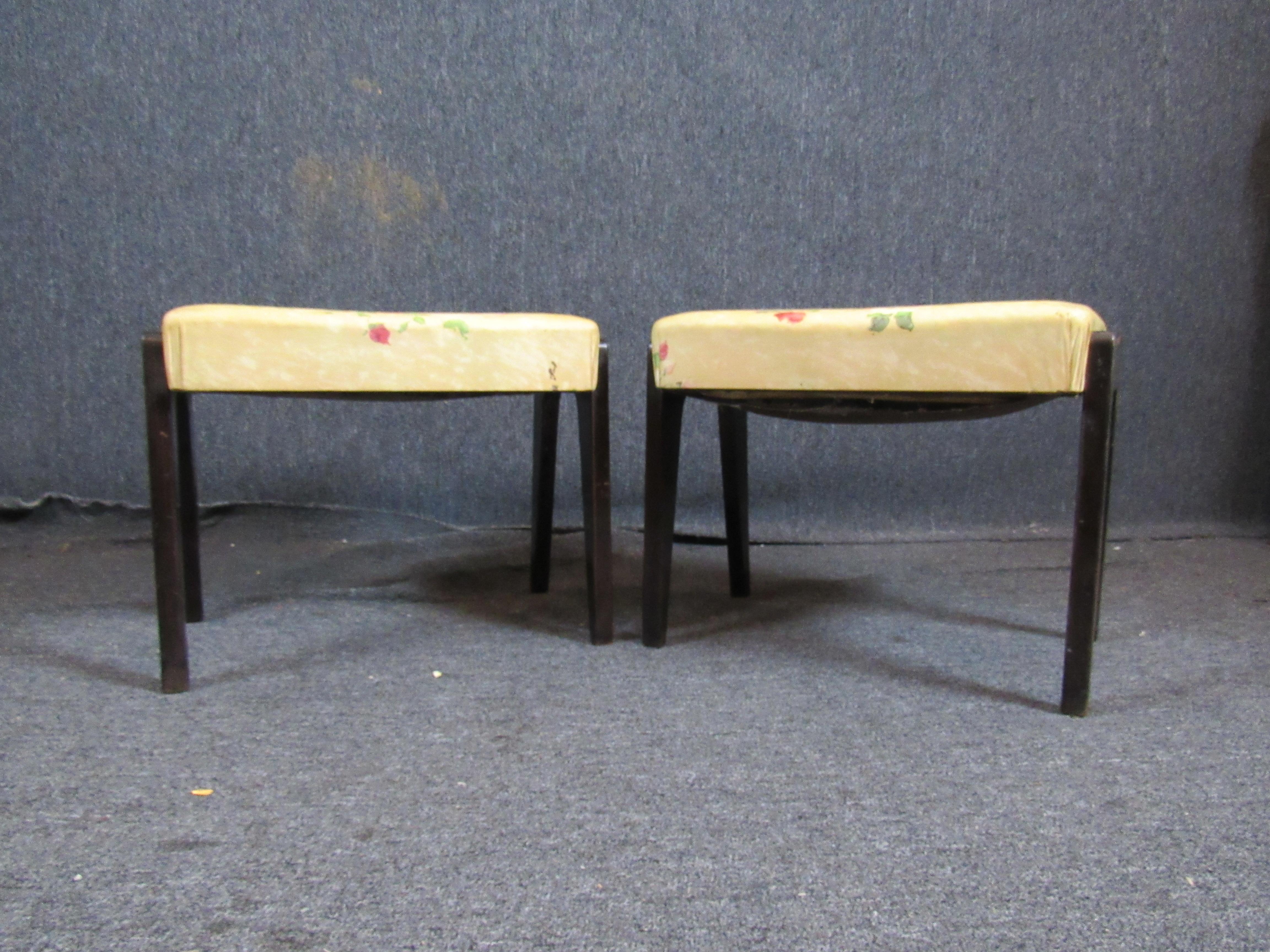 Charming little pair of beautiful vintage mid-century floral print ottomans. The bright, plush cushion accented by striking dark mahogany legs is sure to blend with a wide variety of decorating styles. Great as ottomans, or as children's stools.