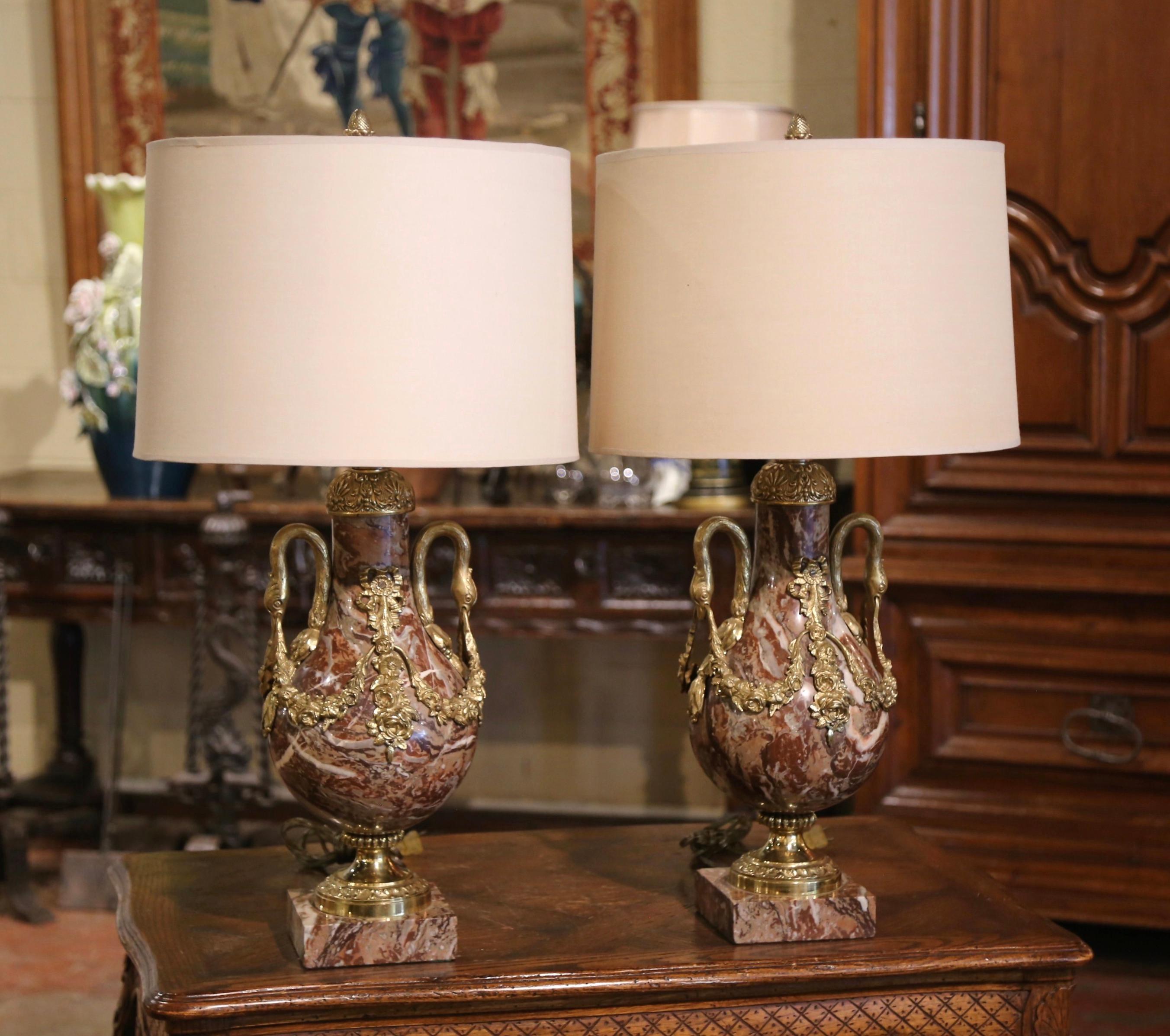 Décorez un buffet, une console ou des tables de chevet avec cette élégante paire de cassolettes anciennes transformées en lampes de table. Fabriquées en France, vers 1920, les urnes sont en marbre panaché sculpté et reposent sur des bases carrées en