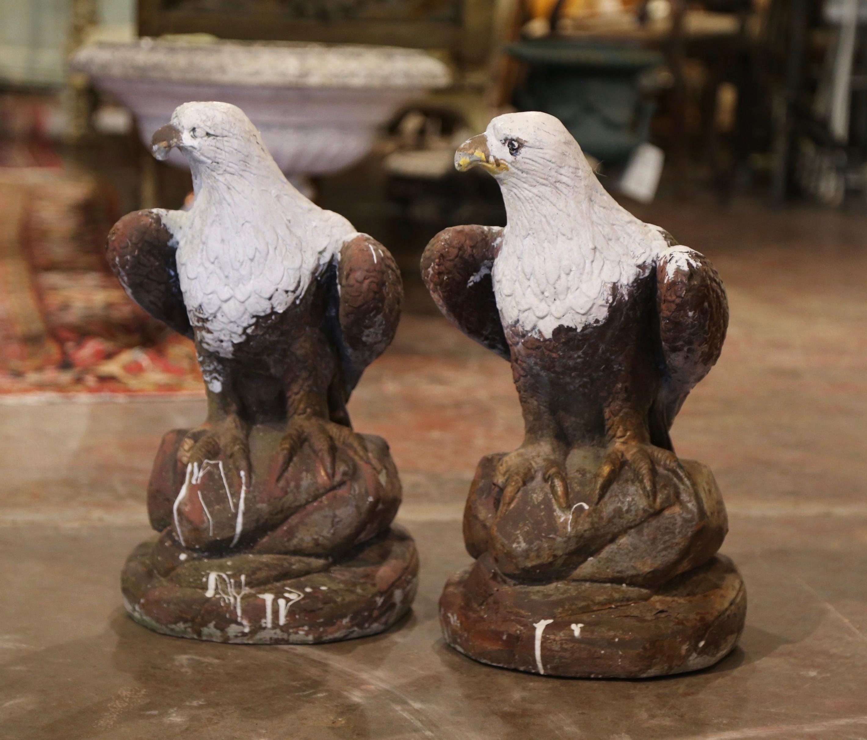 These Classic bird sculptures were crafted in France, circa 1980. The stately, vintage eagles are perched on a rounded rocky base. The sculpted birds have a weathered patinated and painted finish and could be used inside or outside, perhaps on