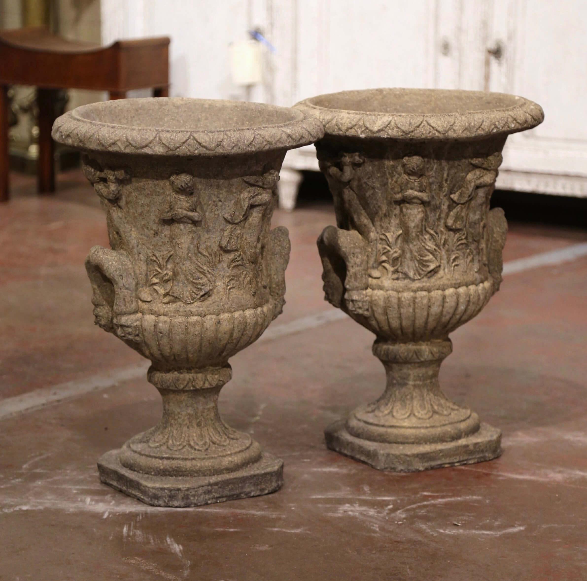 Decorate a patio or garden with this elegant pair of antique outdoor sandstone planters. Carved in France, circa 1970, each flower pot stands on a square base with cut corners over a short pedestal decorated with acanthus leaf motifs. Dressed with