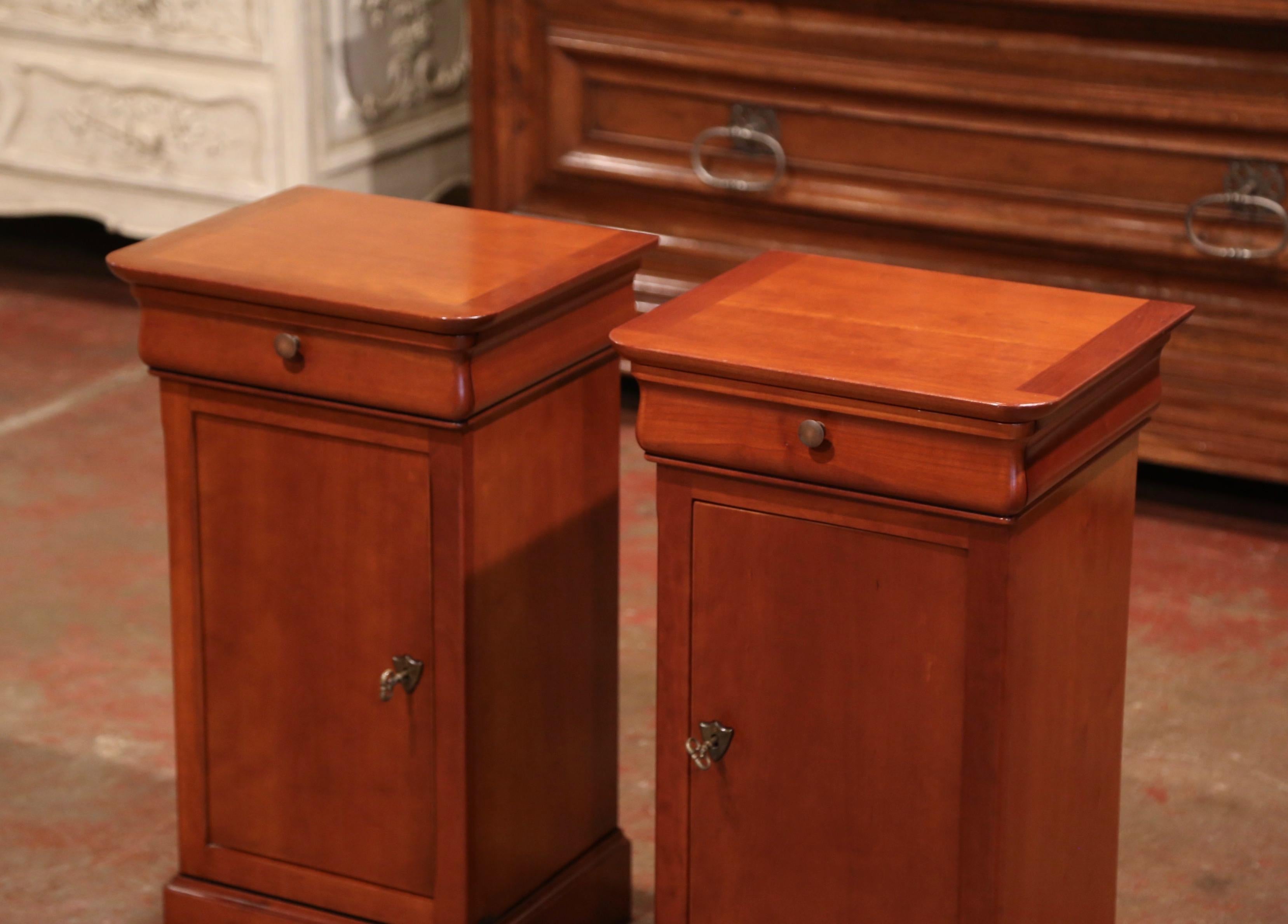 These elegant bedside tables were crafted in France by Grange, circa 1990. Each nightstand features a top drawer embellished with a brass knob, and a long door over a carved bottom plinth. The inside reveals a center shelf for ultimate storage. Both