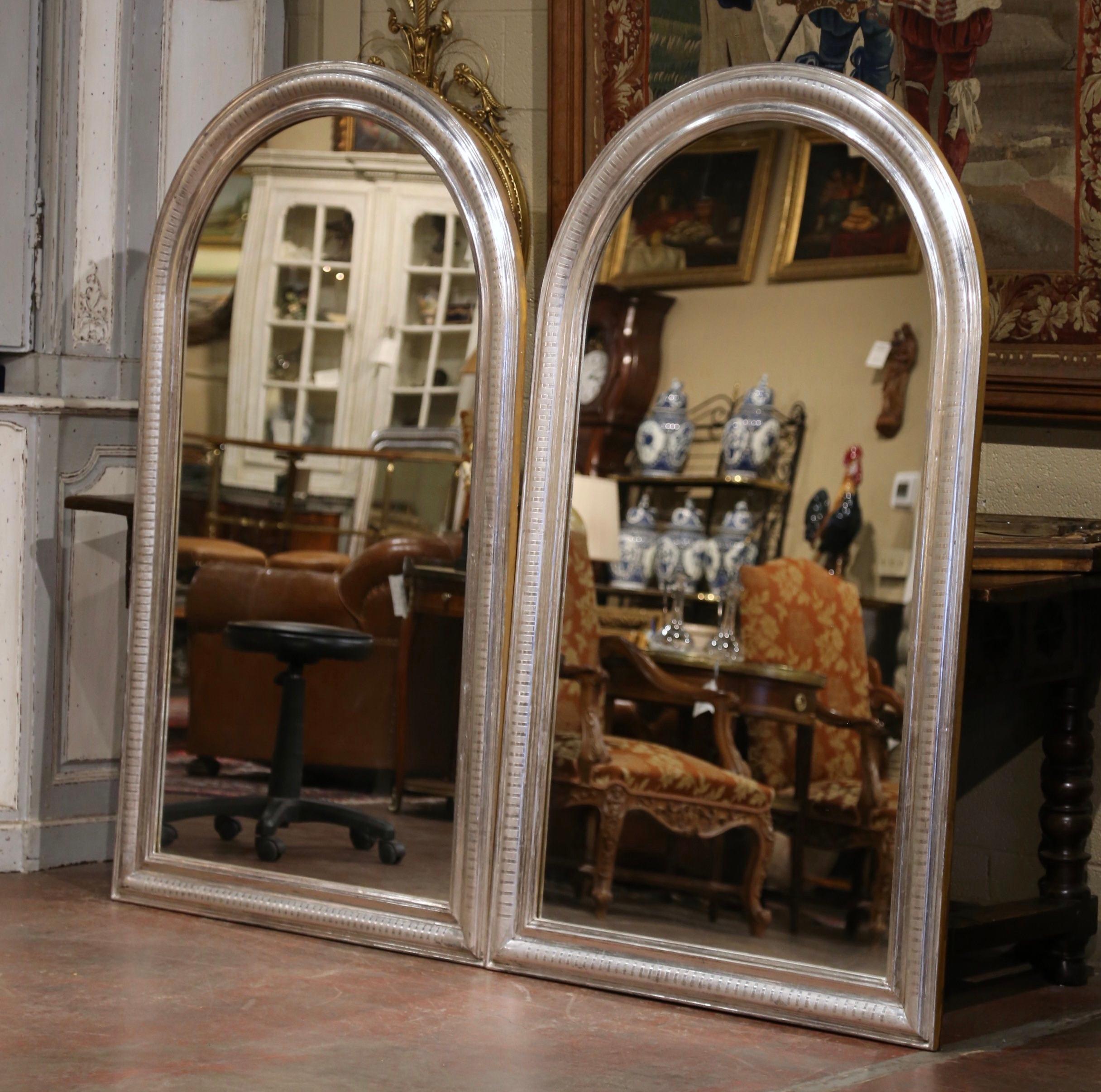 Decorate a master bathroom with this important pair of wall mirrors. Crafted in France, circa 1970 and over 5.5 feet tall, each antique mirror has traditional, timeless lines with an elegant arched top. Each tall frame is decorated with a luxurious
