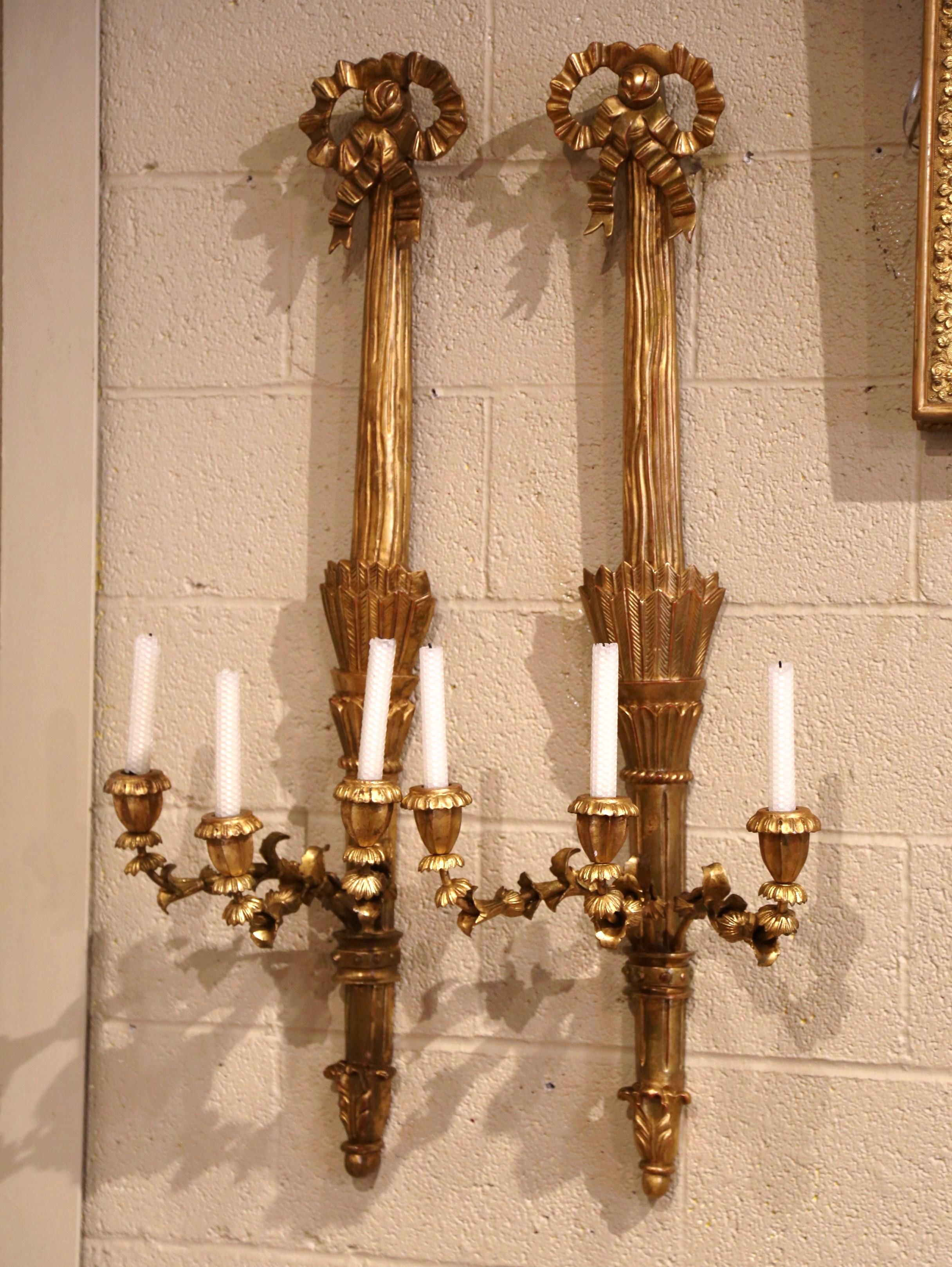 Decorate a living room, dining room or bedroom with this elegant and large pair of decorative sconces; crafted in France circa 1980, each light fixture has three metal arms decorated with floral and acanthus leaf motifs. The sconces feature the