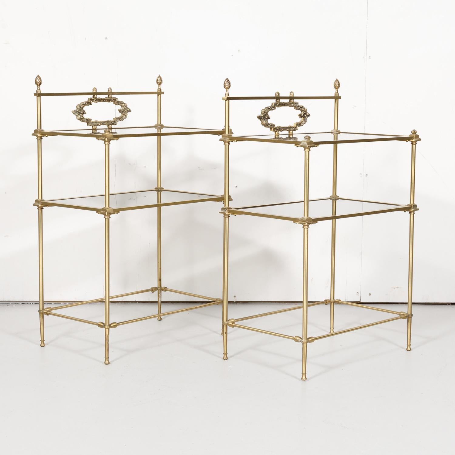A very nice pair of small vintage French Louis XVI style brass tiered shelves or side tables each having two inset smoked glass shelves and decorative brass trim with pinecone finials, circa 1930s. Wonderful as side tables or end tables. Many