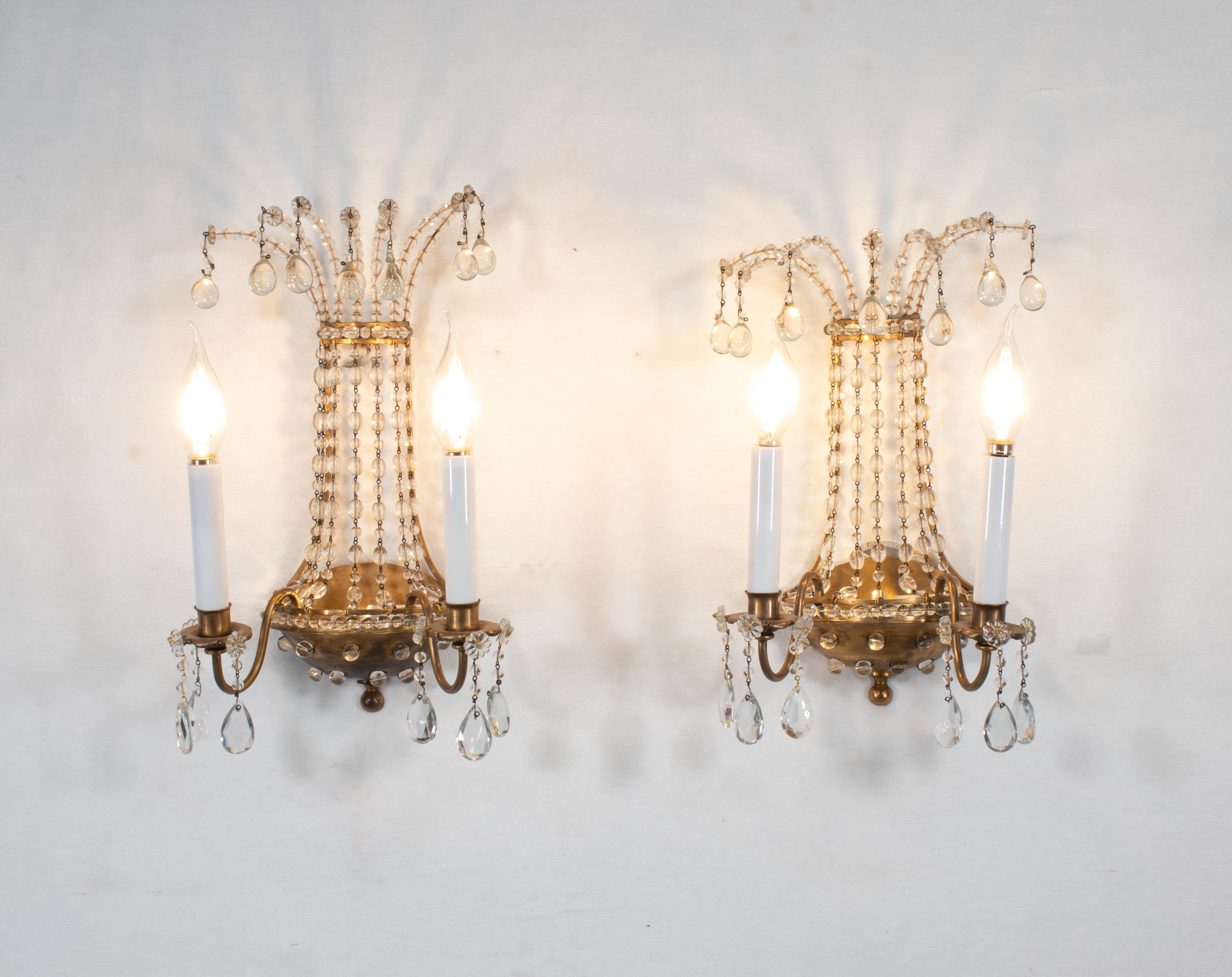 Ces appliques de style Empire mettent en valeur un élément caractéristique de l'éclairage de la Maison Maison : le laiton percé incrusté de cristaux perlés. Cette combinaison complexe de laiton et de perles de cristal incrustées crée un effet visuel