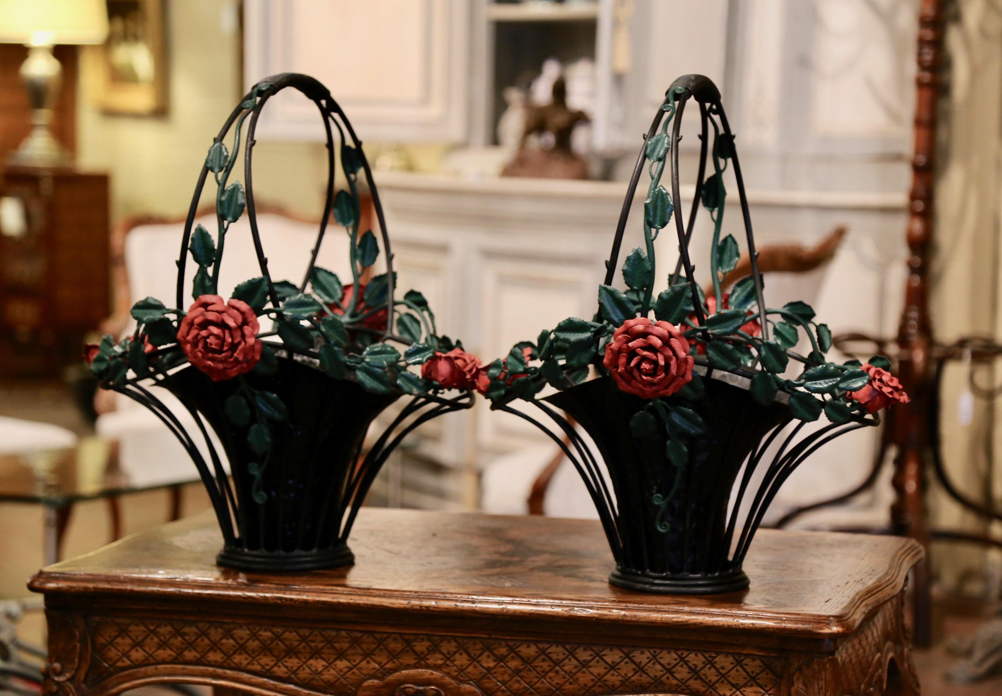 For inside or outside use, these elegant antique baskets were crafted in France circa 1950, made of heavy metal, the large jardinières with tall handles, feature hand painted flowers and leaves around the pierced rim in the red and green palette.