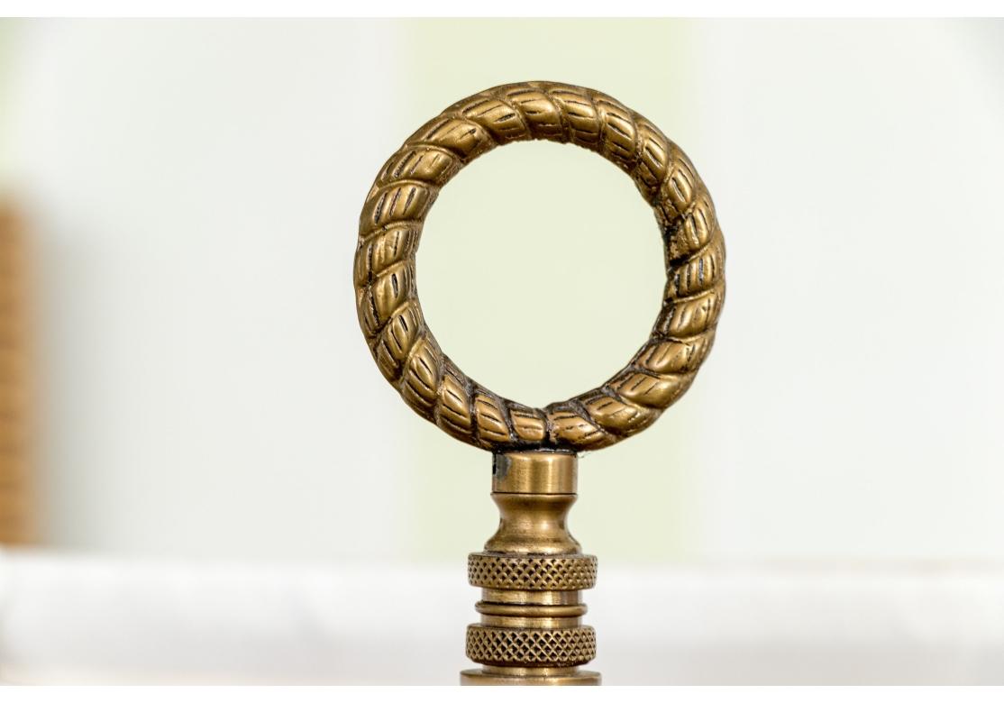 Paire de lampes de table de style français en forme d'urne, avec une double chaîne de traction. Les urnes en métal noir sont dotées de grandes poignées ajourées en métal doré et d'un pied doré. Elle repose sur un large piédestal en forme et cannelé,
