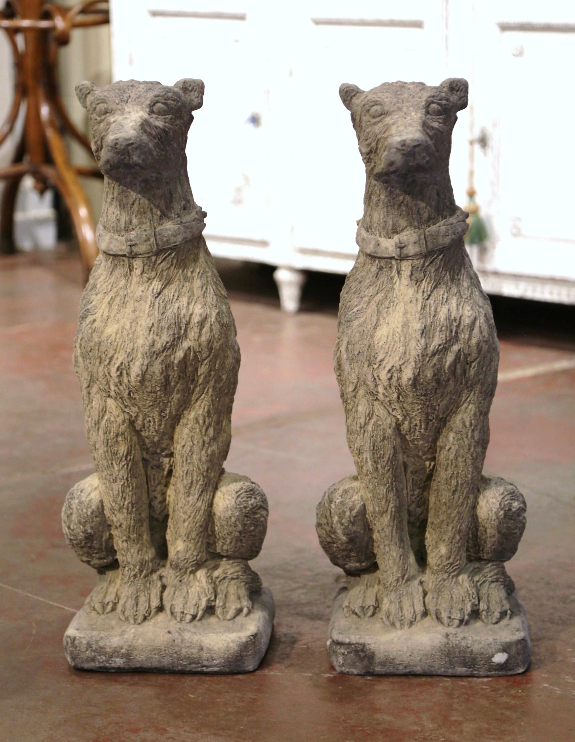 Carved of stone circa 2000, the tall vintage deerhounds are set on a flat square base; sited on their back legs, both canines have a proud expression with detailed fur and further embellished with a collar around their neck. The garden sculpted