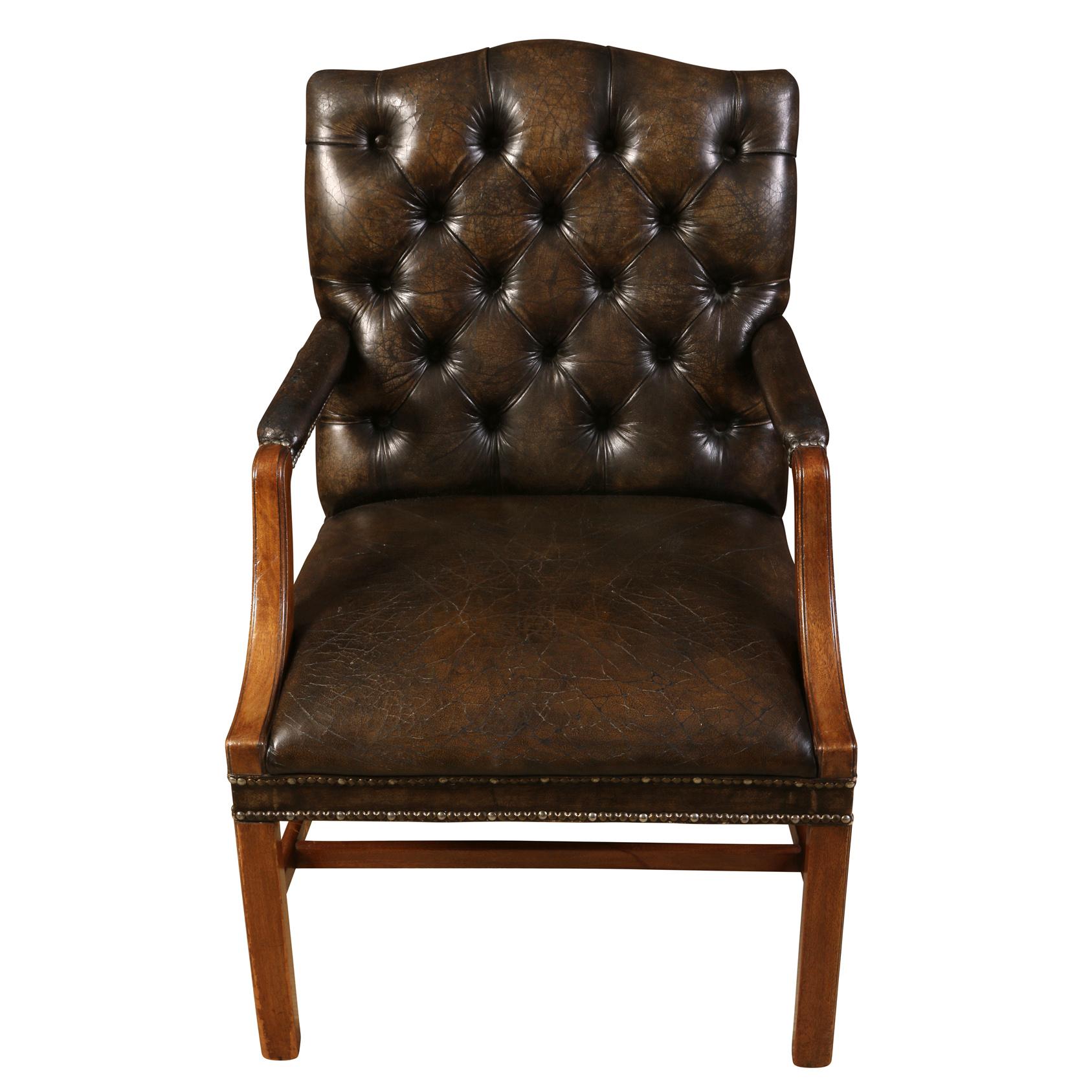 A pair of vintage, Georgian style, patinated leather tufted back arm chairs.  The brown leather features intentional distress marks to the seat which suit the antique, aged appearance.  The chair frames date to early 20th Century and the leather