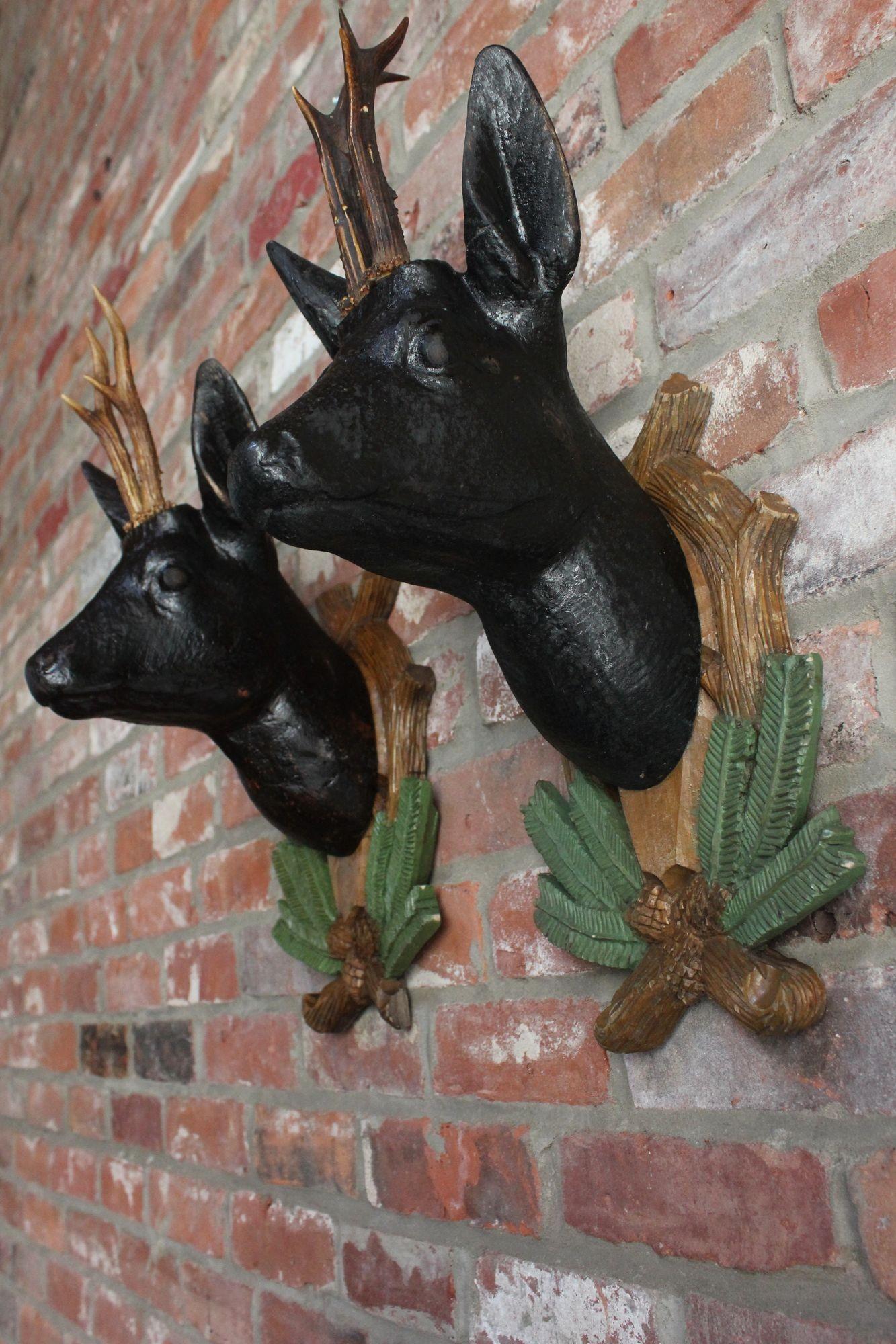 Set of two similar Black Forest carved and hand-painted 'stag' sculptures with real antlers mounted to decorative 'wreath' plaques for wall hanging (ca. 1930s/40s, Germany).
One deer is slightly darker than the other, apparent only in direct