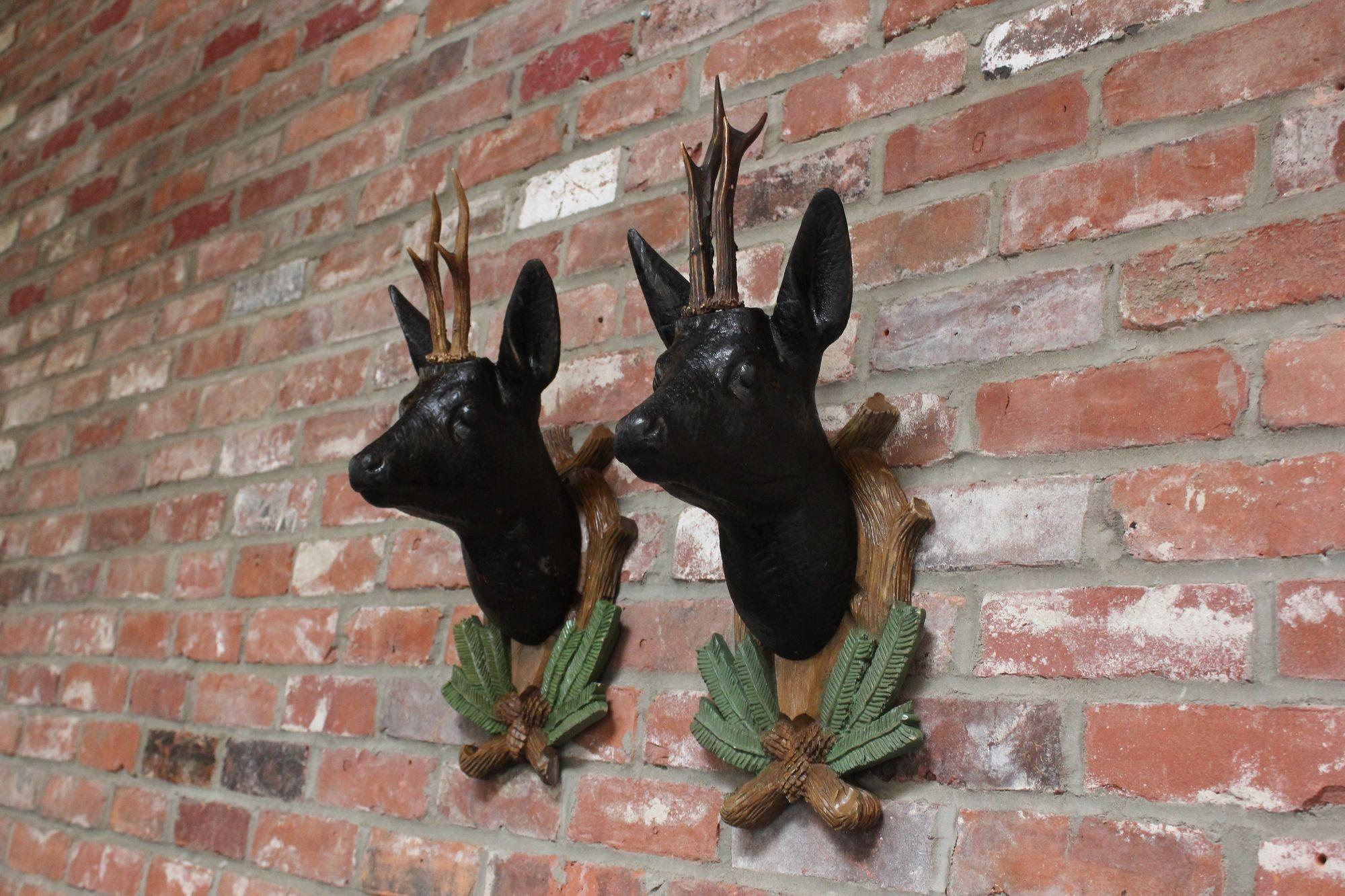 Ensemble de deux sculptures similaires de cerfs de la Forêt Noire, sculptées et peintes à la main avec de vrais bois, montées sur des plaques décoratives en forme de couronnes pour être accrochées au mur (vers les années 1930/40, Allemagne).
L'un