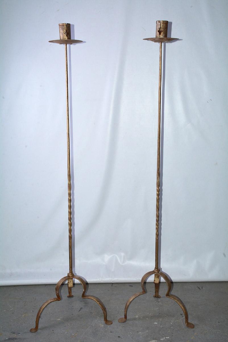 Rustic and elegant, each of the pair of vintage gilt handcrafted wrought iron tall stand candleholders or floor torchières has three curved legs, partially twisted decorative shafts and bobeches. The candle sockets have 2