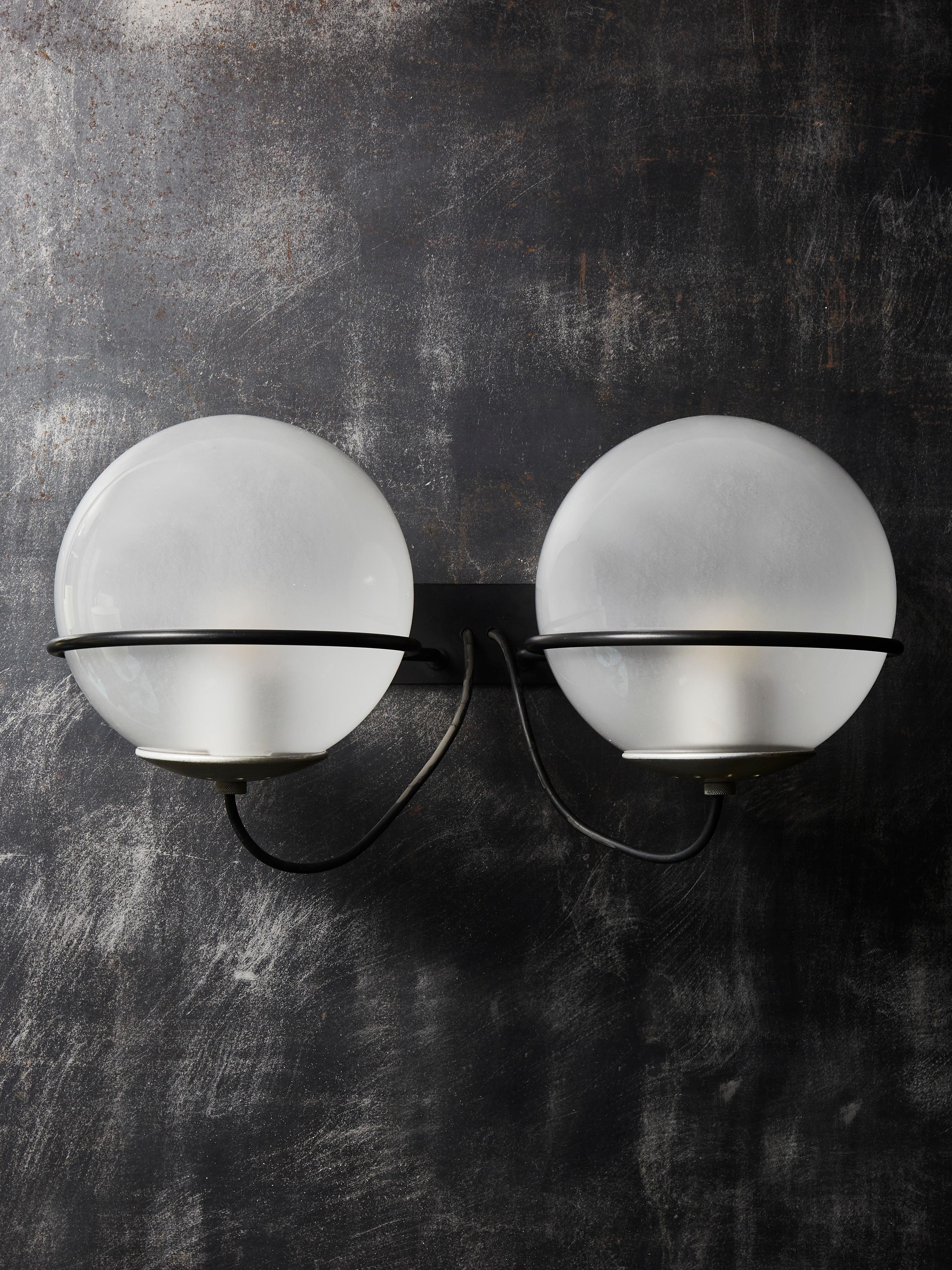 Original pair of vintage model 237/2 wall sconces by Gino Sarfatti for Arteluce.

Two frosted glass globes resting on the black lacquered iron bar support rings. Closed with oxidized aluminium plate.

Original sticker on the backplate.
 